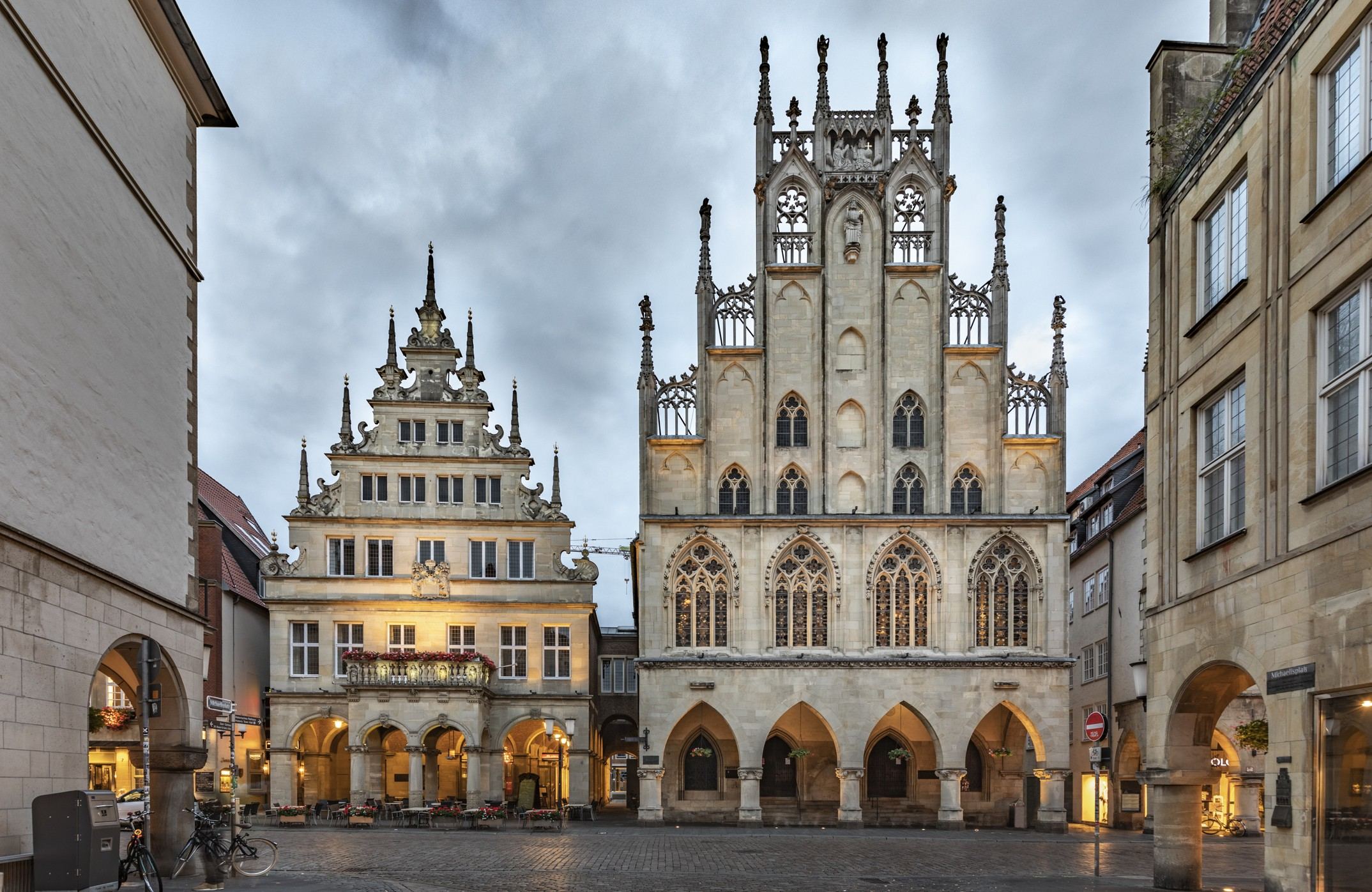 Blick auf das historische Rathaus mit gotischer Fassade und dem angrenzenden Renaissance-Gebäude am belebten Marktplatz, umgeben von weiteren historischen Gebäuden unter bewölktem Himmel. Blick auf das historische Rathaus mit gotischer Fassade und dem angrenzenden Renaissance-Gebäude am belebten Marktplatz, umgeben von weiteren historischen Gebäuden unter bewölktem Himmel.