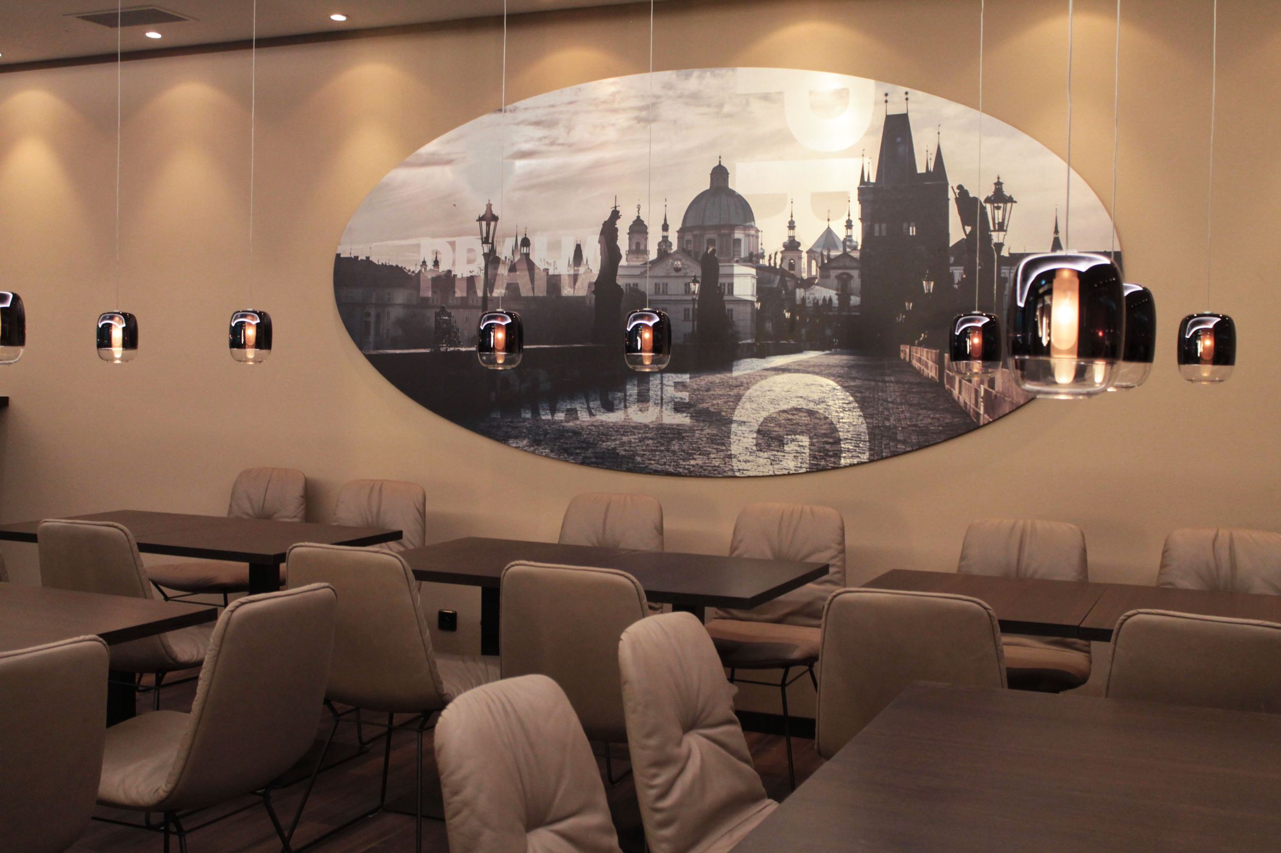 hotel Prague Florentinum Motel One tables and chairs with Prague cityscape on the wall