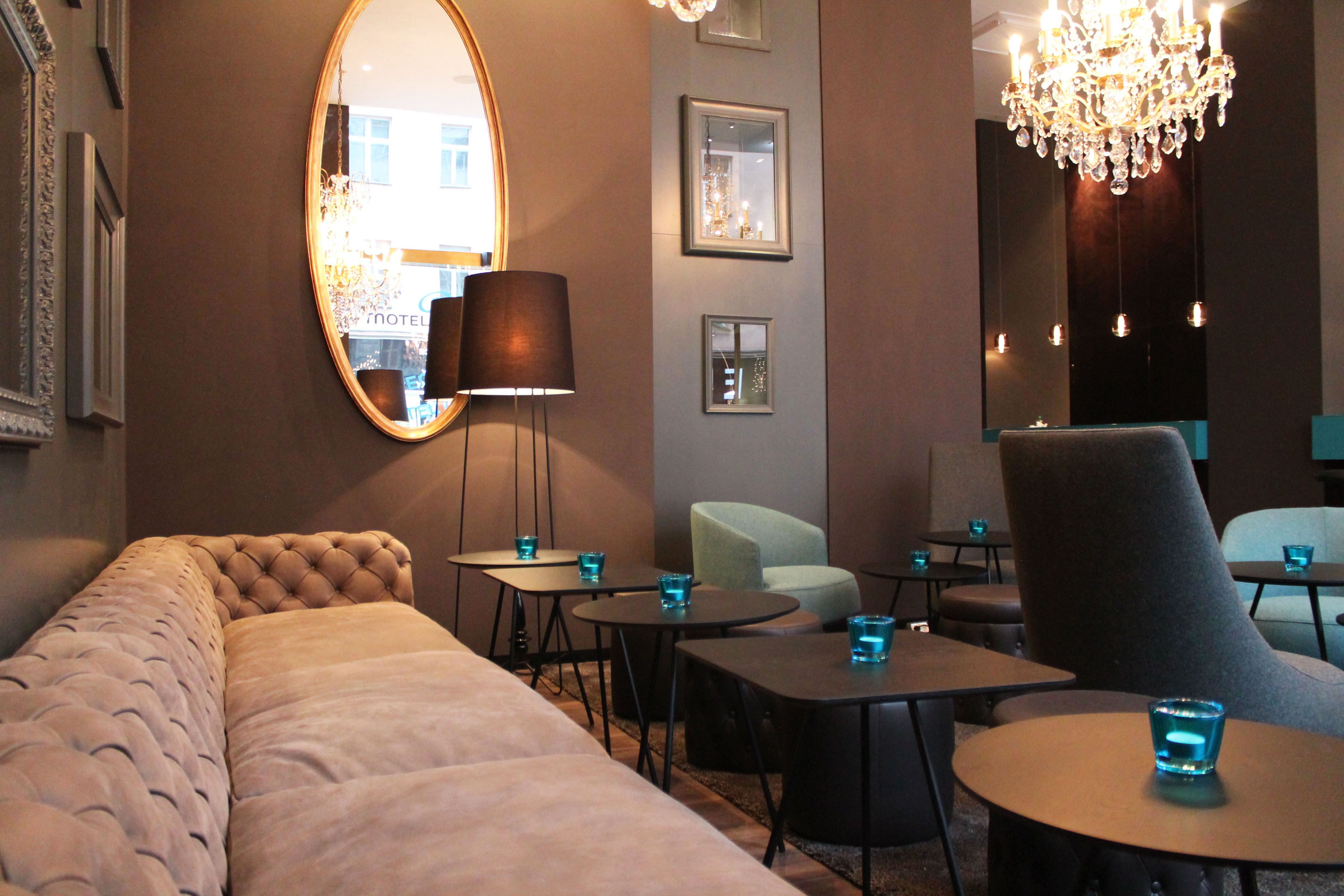 Hotel Prag Florentinum Motel One Lounge mit großer Couch, Tischen und Spiegel an der Wand