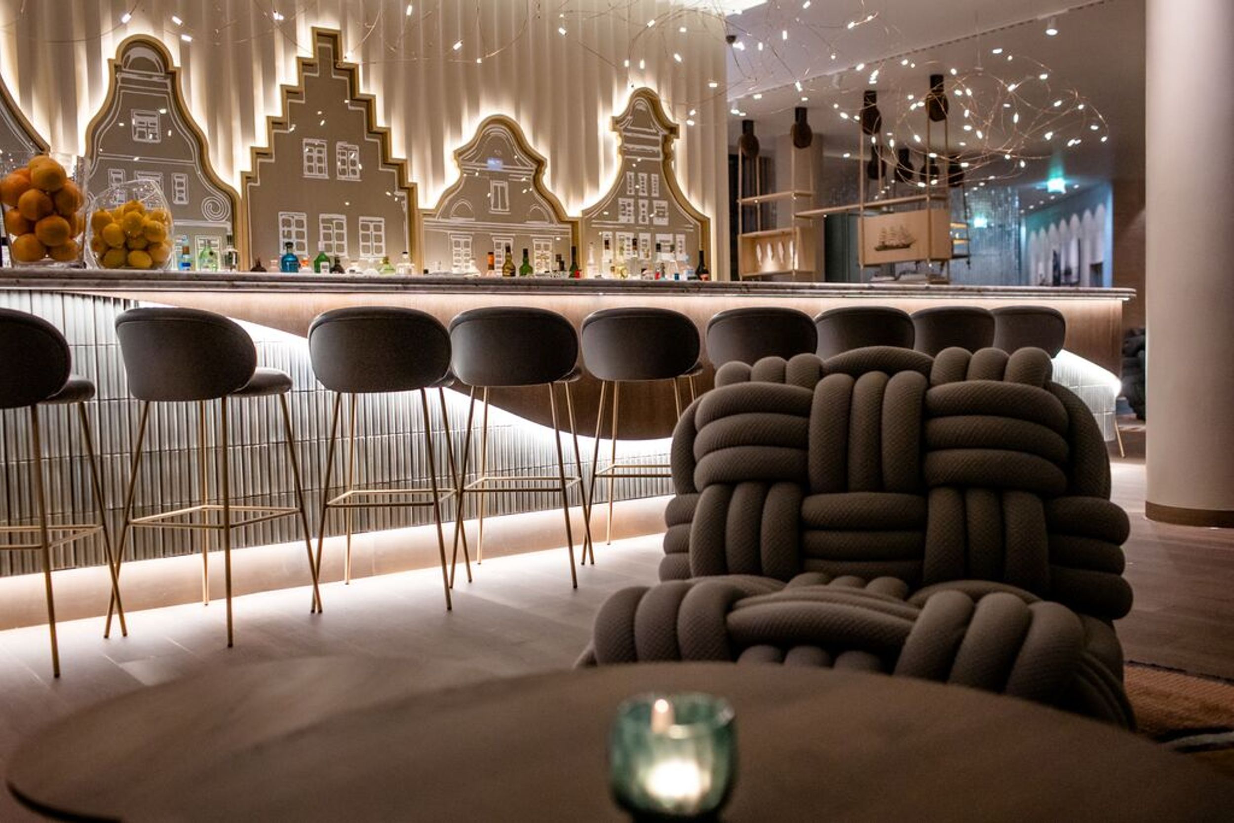 Designhotel Rostock Motel One Bar mit Barhockern an Tresen sowie Knotensessel im Vordergrund