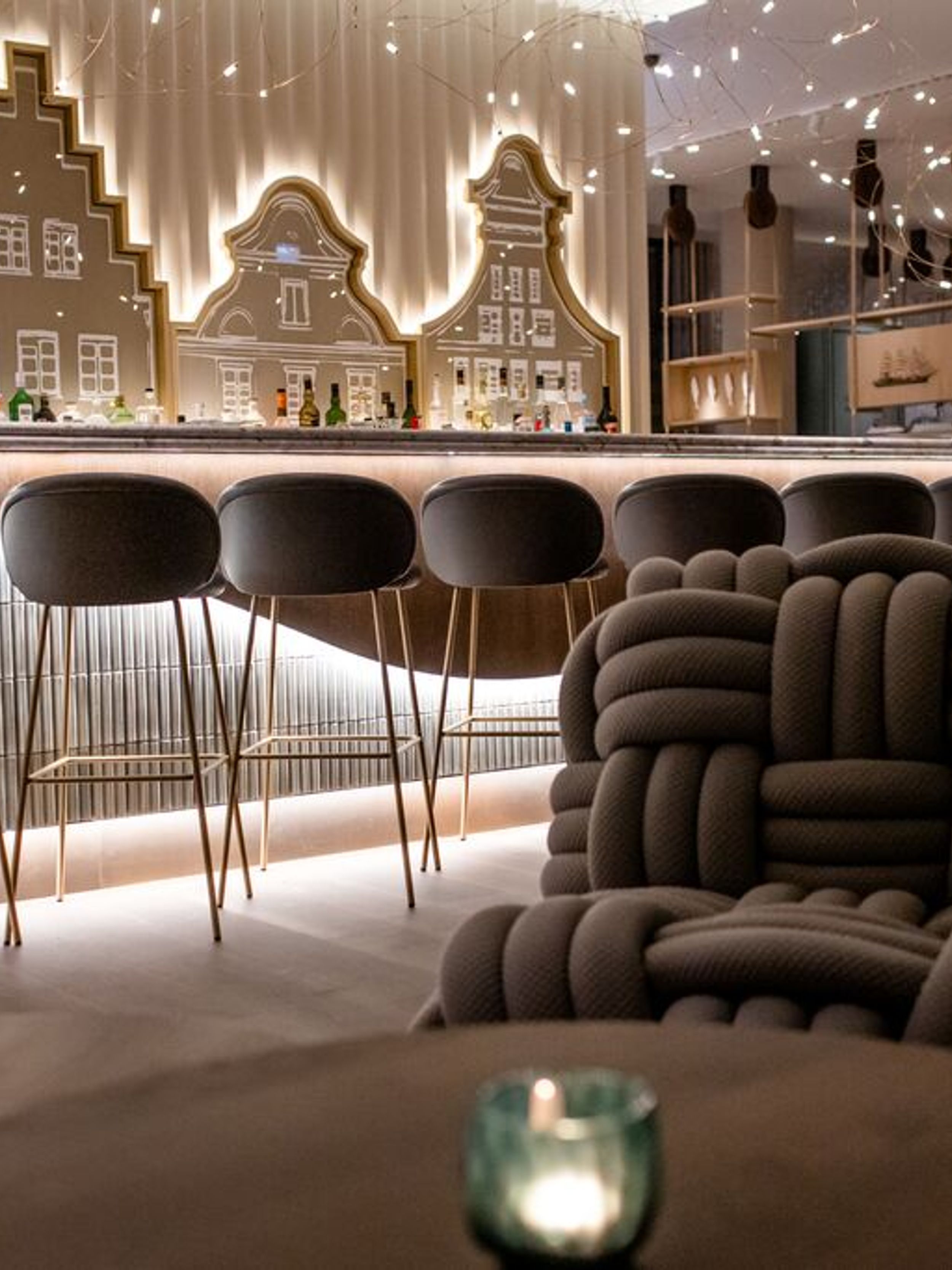 Designhotel Rostock Motel One Bar mit Barhockern an Tresen sowie Knotensessel im Vordergrund