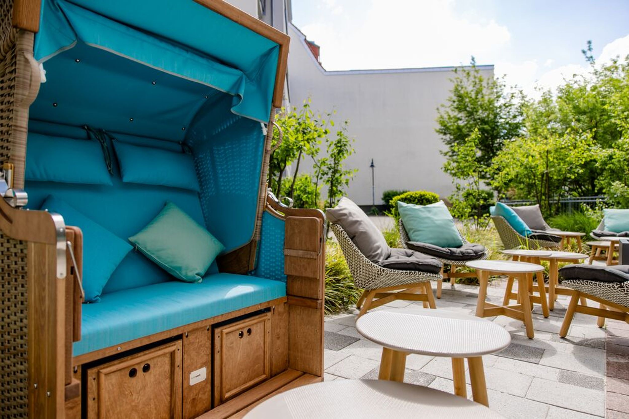 Designhotel Rostock Motel One Außenbereich mit Strandkorb und weiteren Sesseln