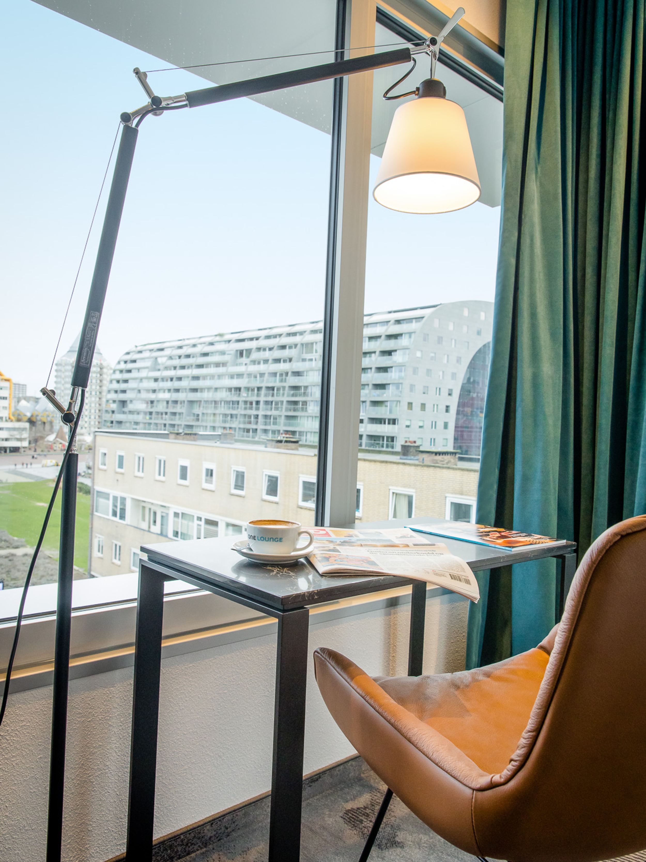 Hotel Rotterdam Motel One Schreibtisch, Stuhl und Lampe vor großem Fenster mit Blick auf die Markthalle