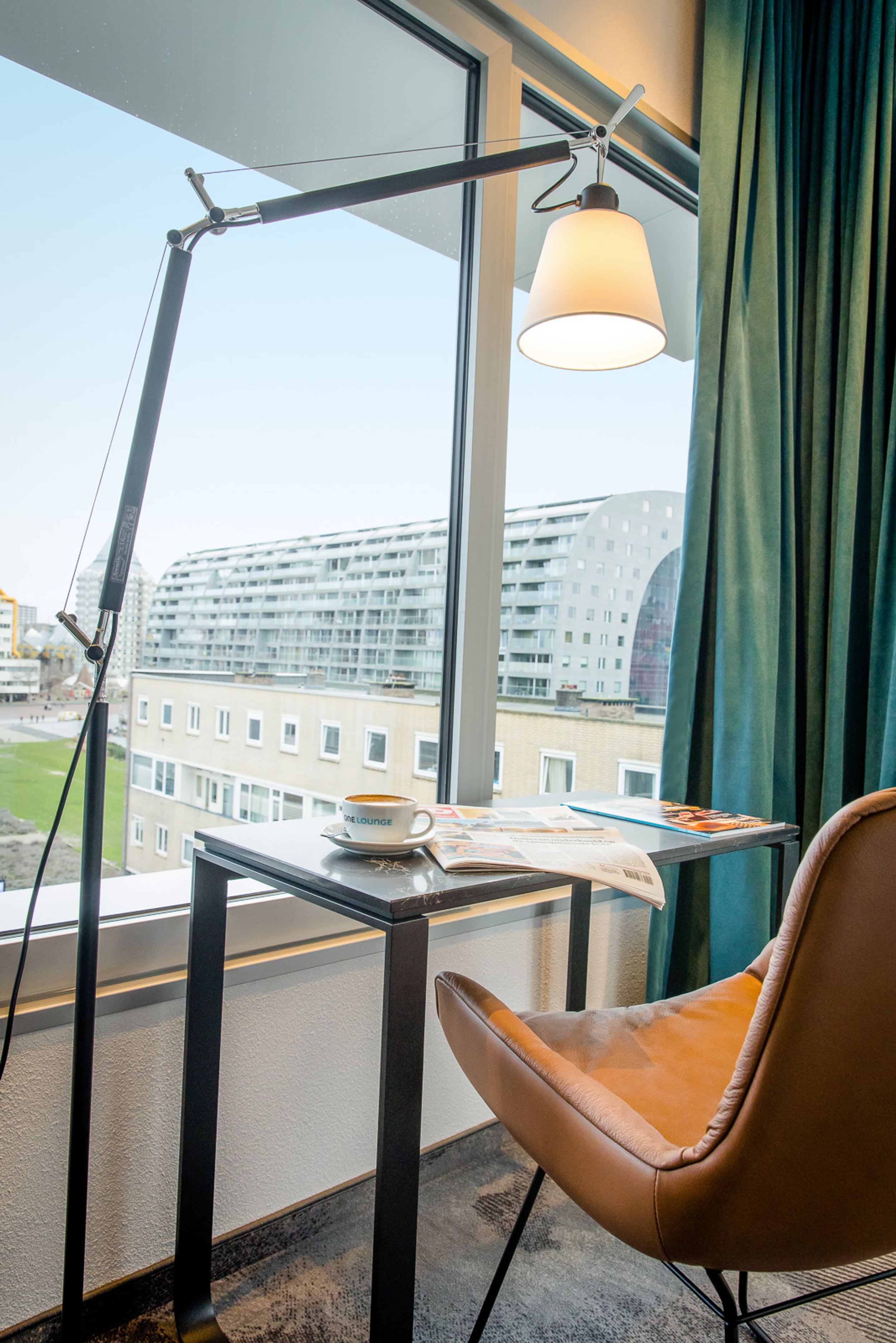 Hotel Rotterdam Motel One Schreibtisch, Stuhl und Lampe vor großem Fenster mit Blick auf die Markthalle