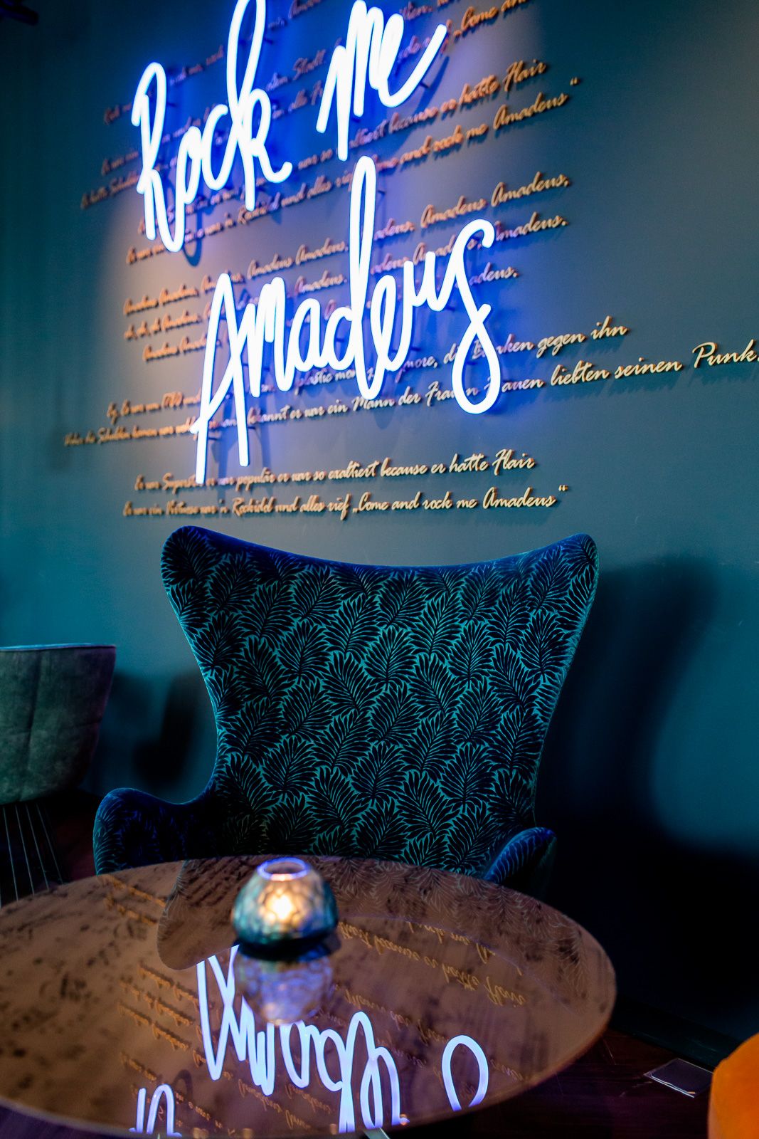 Hotel Salzburg Mirabell Motel One Sessel und Tisch sowie Neonschrift "Rock me Amadeus" an der Wand