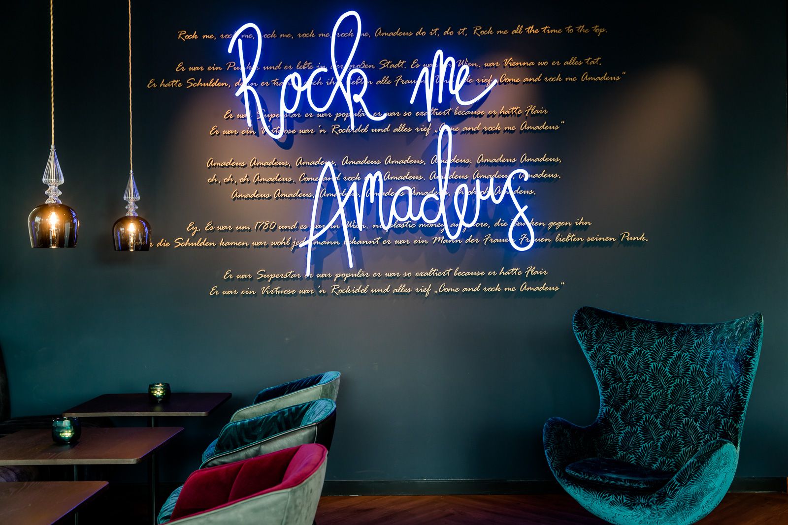 Hotel Salzburg Mirabell Motel One Lounge mit Egg Chair und Leuchtschrift "Rock me Amadeus" an der Wand