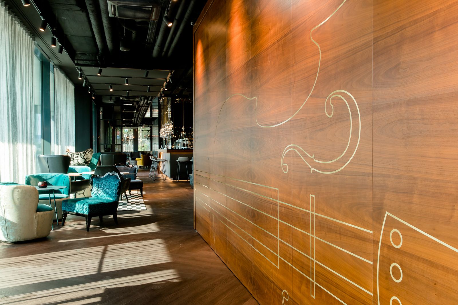 Designhotel Salzburg Mirabell Motel One große Holzwand in lichtdurchfluteter Lounge und Bar im Hintergrund