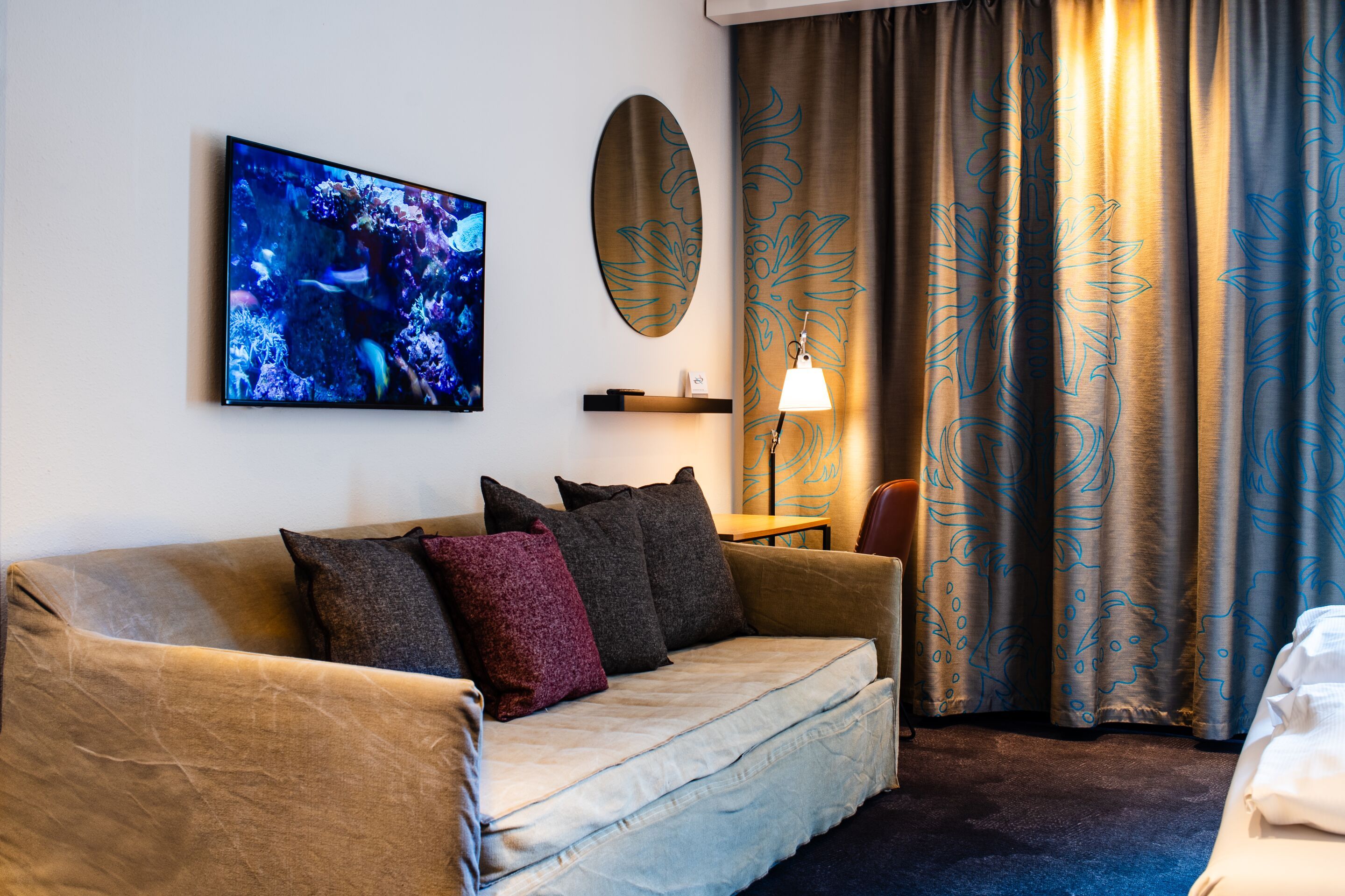 Hotel Stuttgart Mitte Motel One seitlicher Blick auf große Couch sowie Tisch und Stuhl