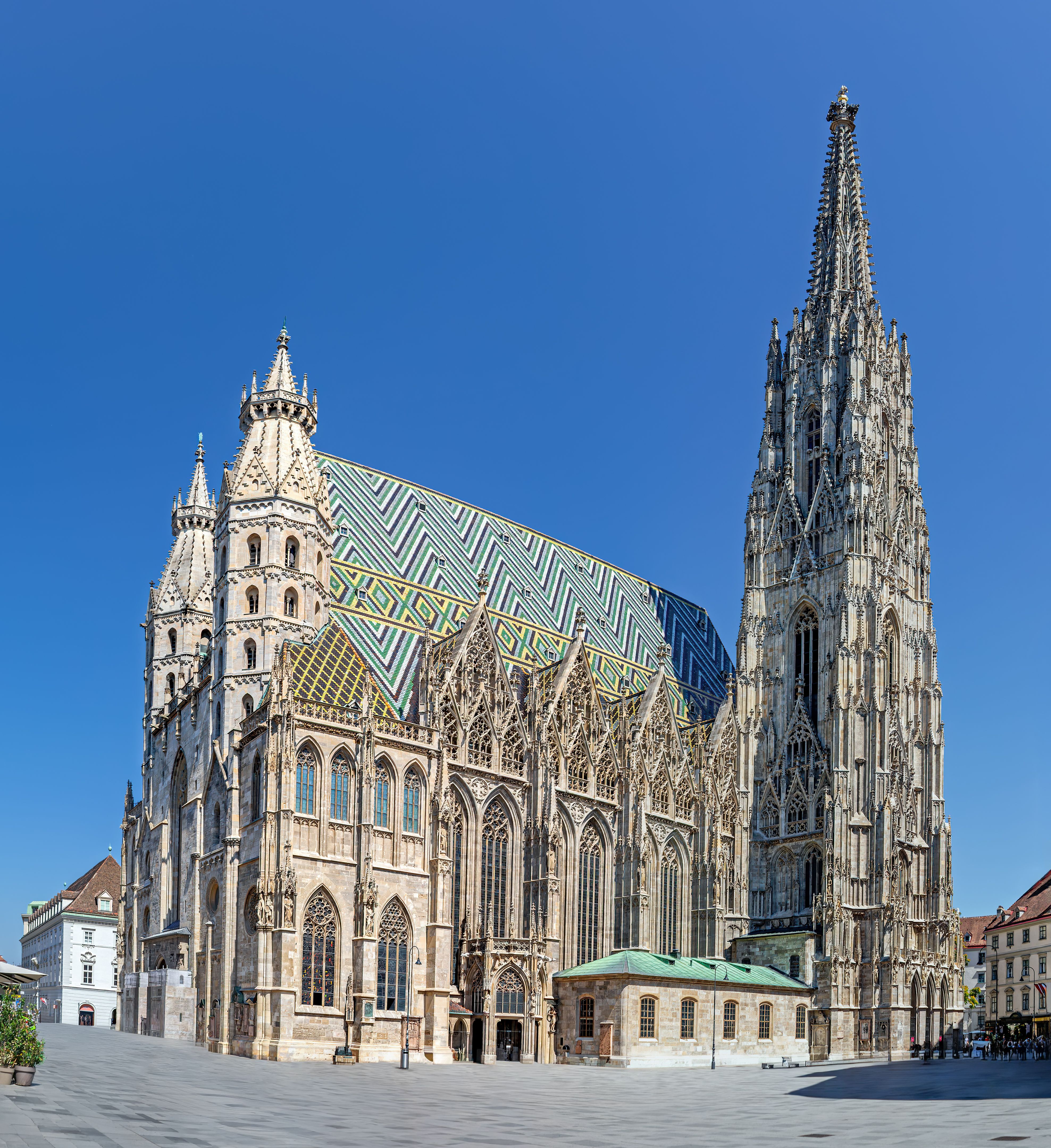 Gotischer Stephansdom in Wien mit farbigem Ziendach und hohem Turm unter klarem blauem Himmel.