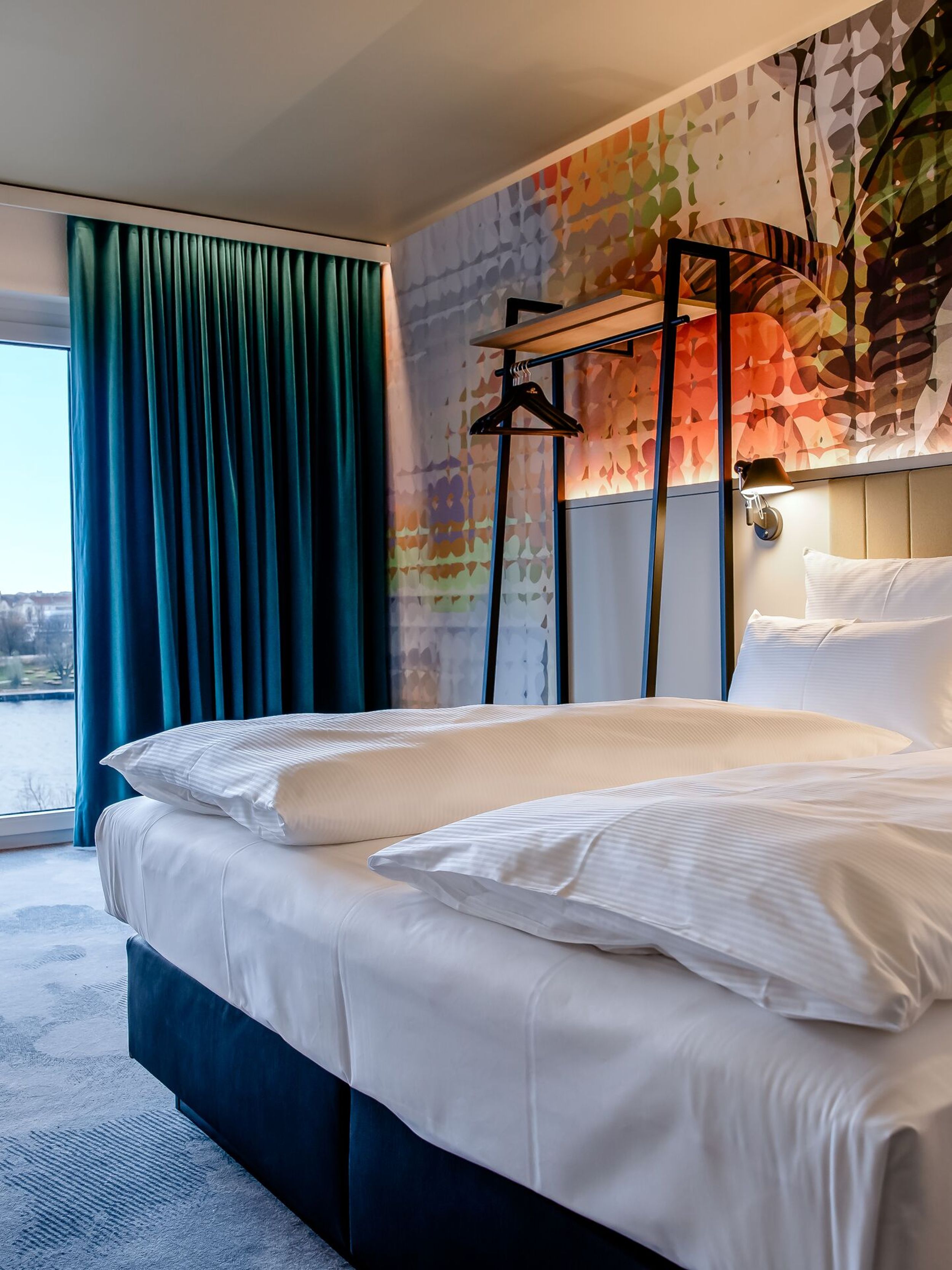 Hotel Wien Donau City Motel One seitlicher Blick in geräumiges Zimmer mit Doppelbett und Blick auf die Donau