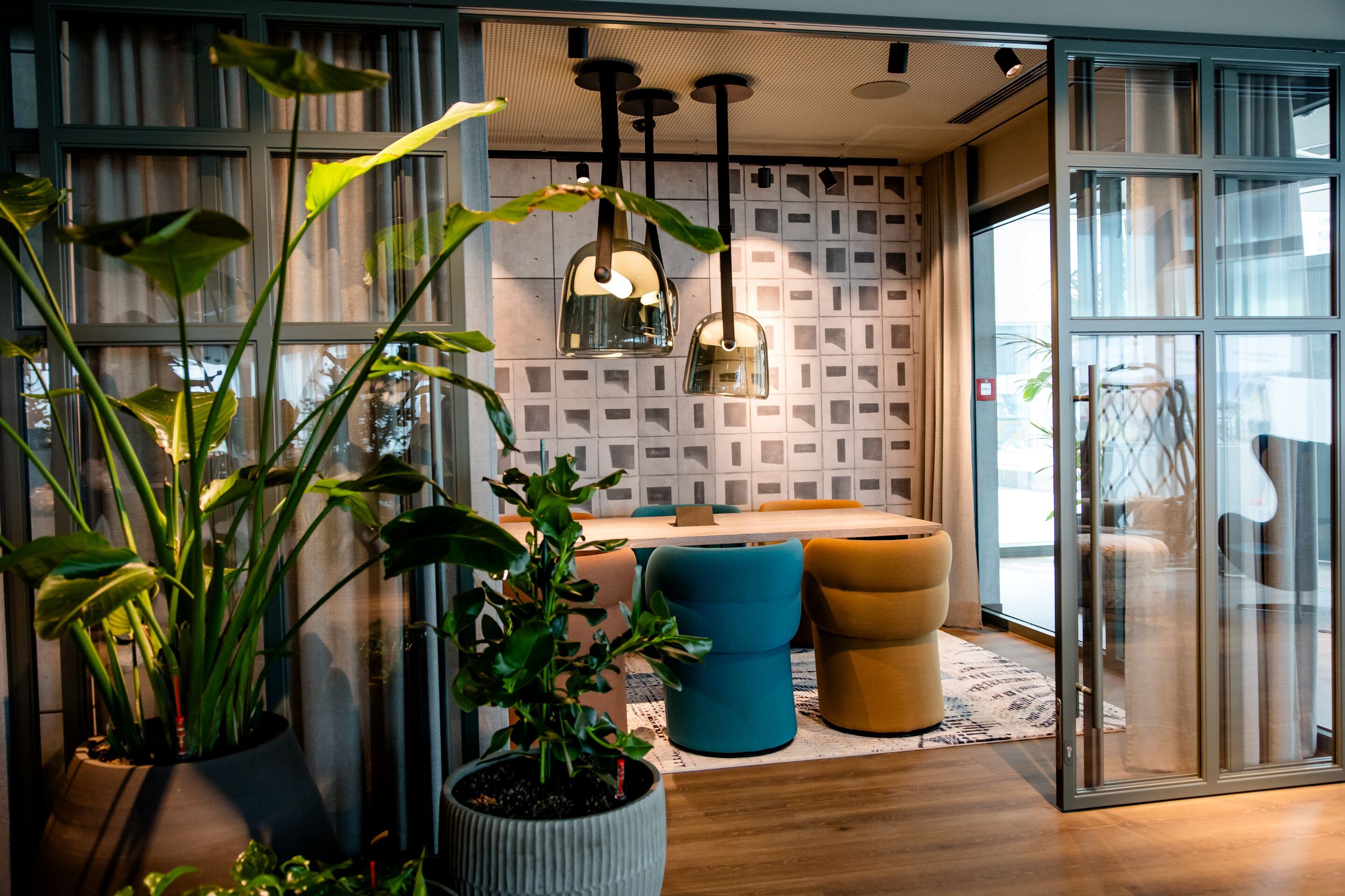 Hotel Vienna Donau City Motel One view through an open glass door into a meeting room with plants in the foreground