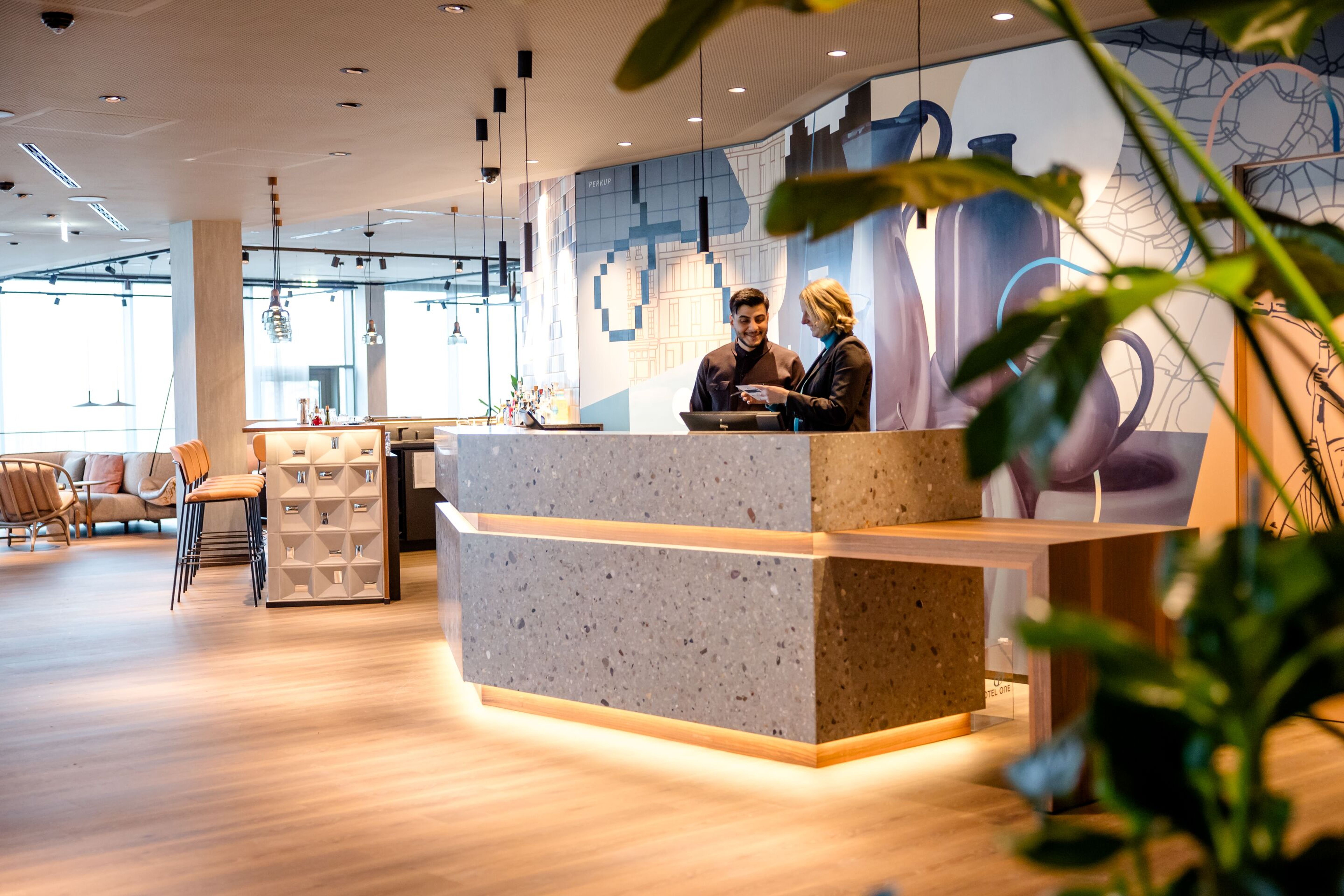 Designhotel Wien Donau City Motel One seitlicher Blick auf die Rezeption mit zwei Mitarbeitenden Designhotel Wien Donau City Motel One seitlicher Blick auf die Rezeption mit zwei Mitarbeitenden