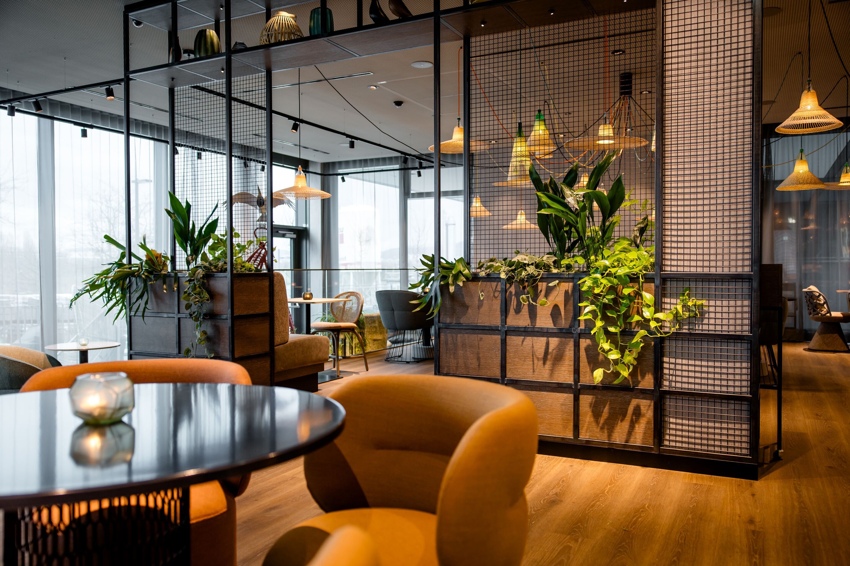 Designhotel Wien Donau City Motel One helle Lounge mit mehreren Sitzgelegenheiten sowie großes offenes Regal mit Pflanzen
