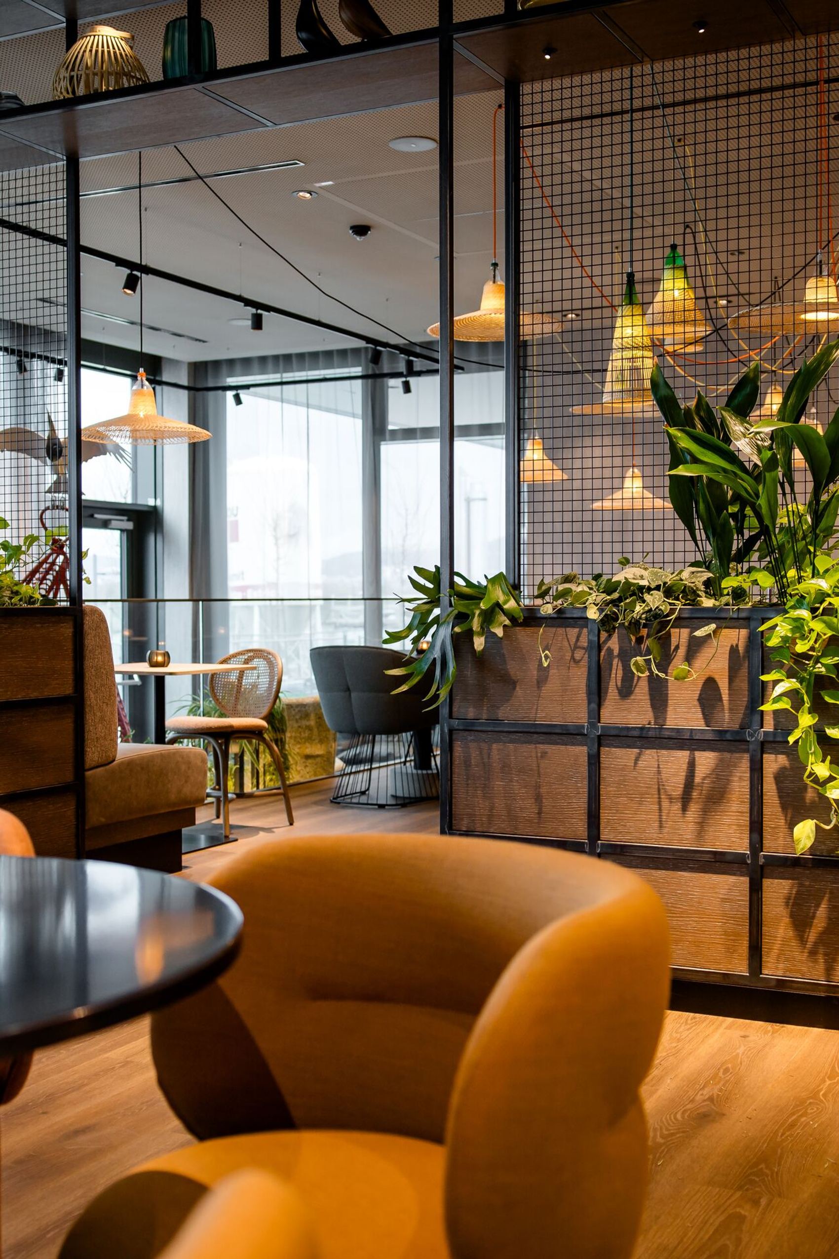 Designhotel Wien Donau City Motel One helle Lounge mit mehreren Sitzgelegenheiten sowie großes offenes Regal mit Pflanzen