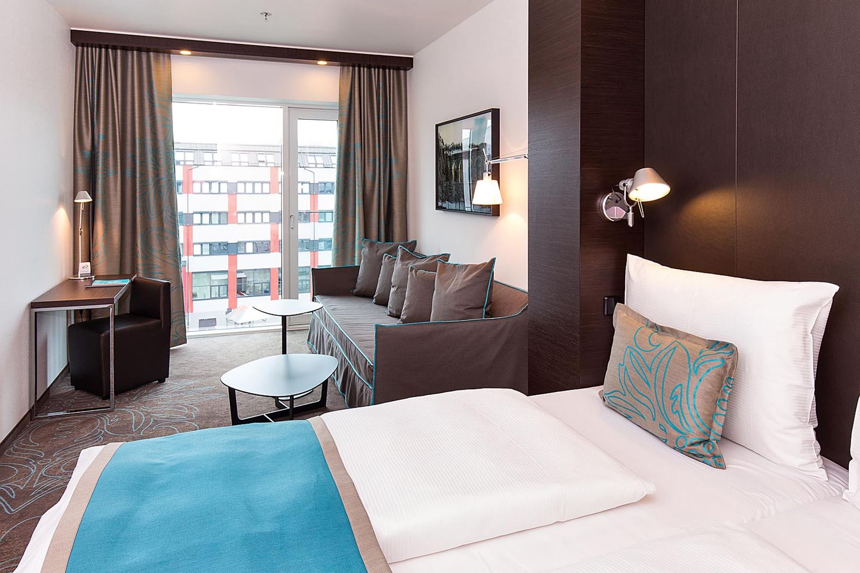 Designhotel Wien Hauptbahnhof Motel One großes Zimmer mit Bett, Couch, Tisch und Sessel