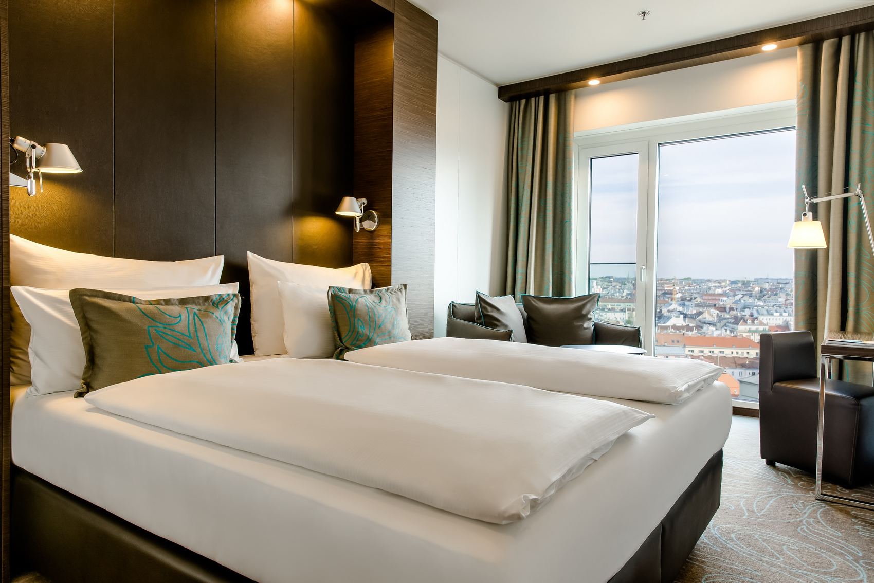 Designhotel Wien Hauptbahnhof Motel One lichtdurchflutetes Zimmer mit Bett und Zierkissen