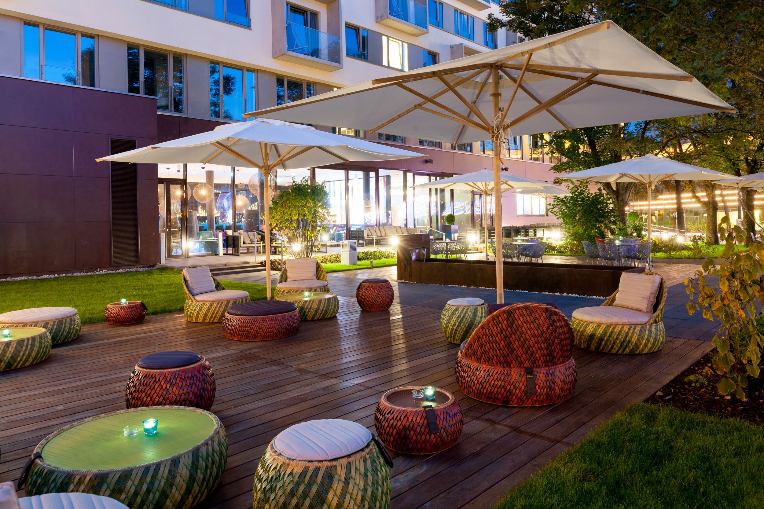 Hotel Wien Prater Motel One Außenbereich mit Sitzgelegenheiten und Sonnenschirm