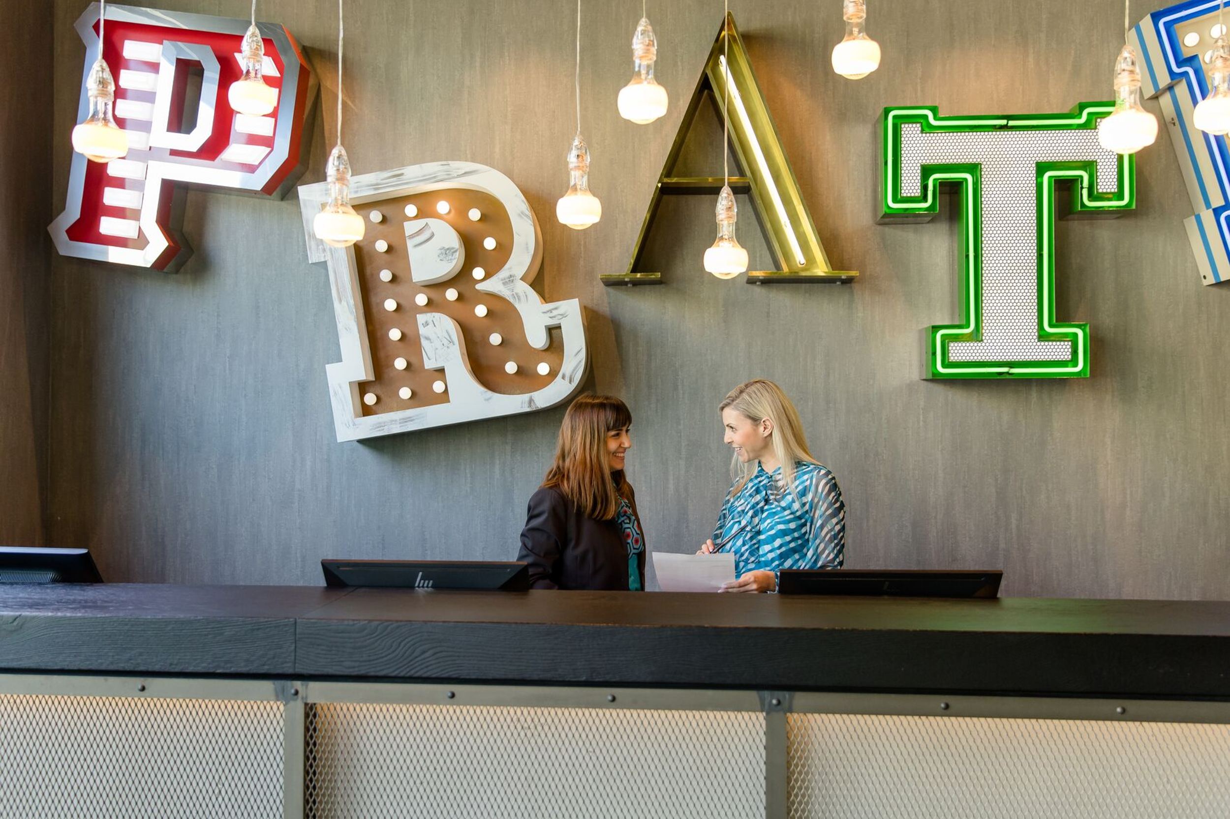 Designhotel Wien Prater Motel One Rezeption mit zwei Mitarbeitenden