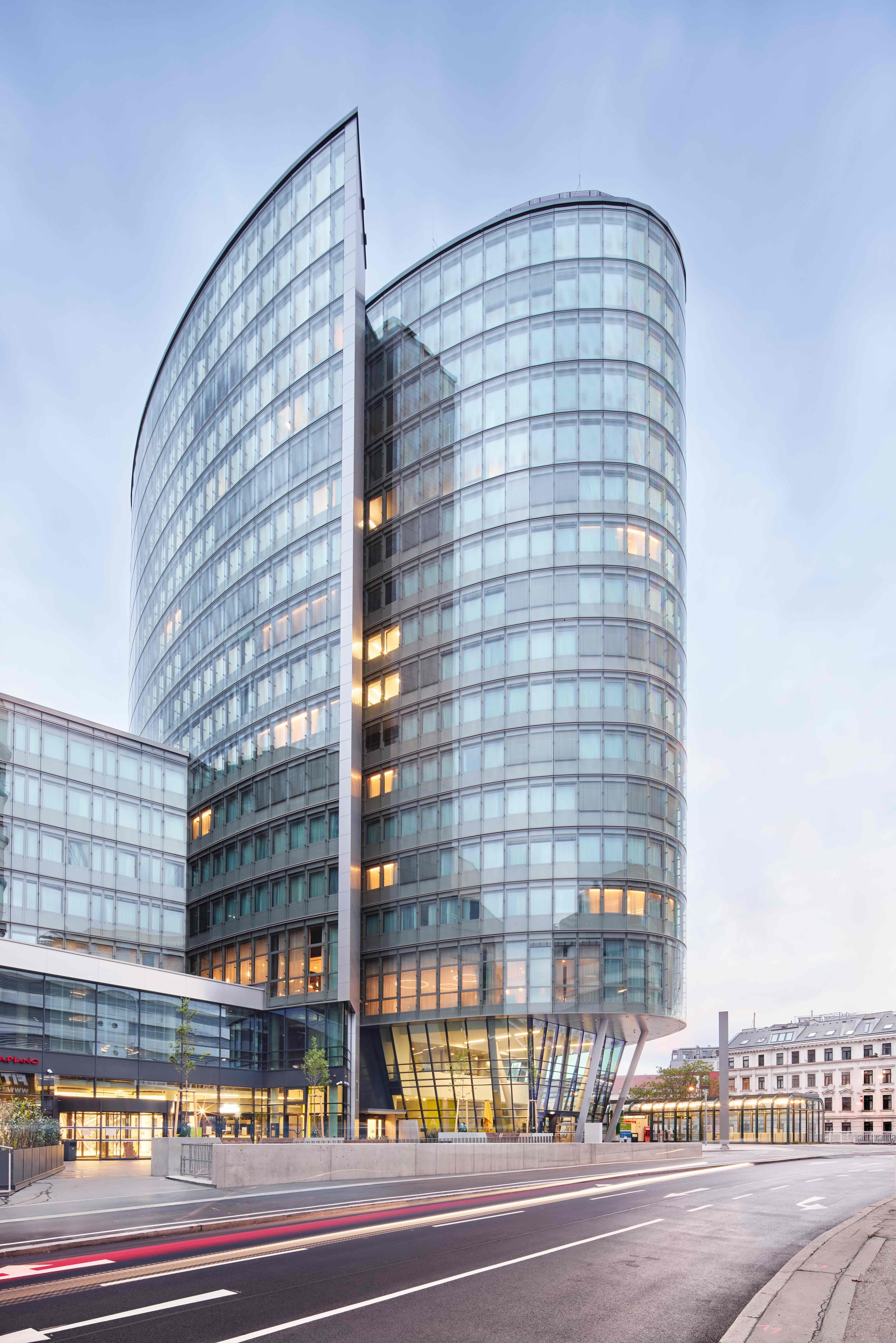 Moderner, eleganter Hotelturm mit geschwungener Glasfassade, der stilvolle Unterkünfte und urbane Aussicht für Geschäftsreisende und Städteurlauber bietet.