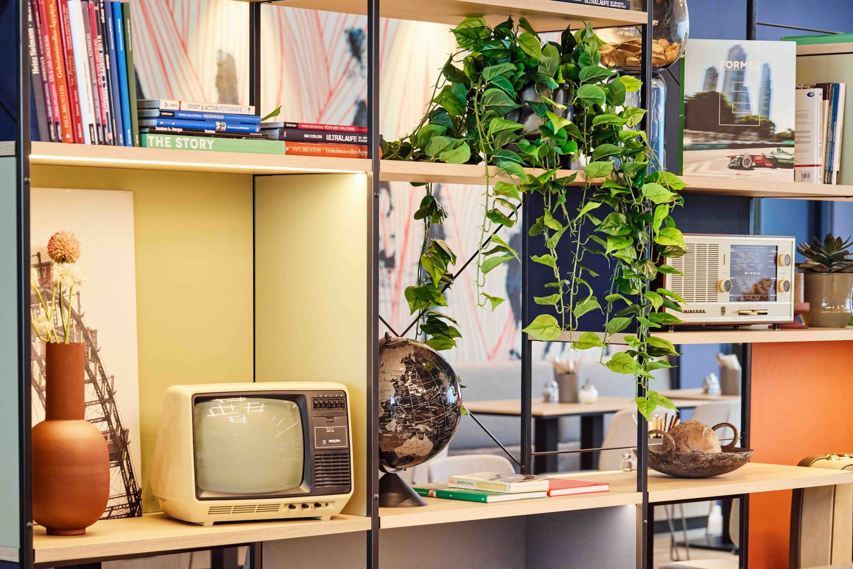 Regal mit Retro-TV, Büchern, gründer Zimmerpflanze und dekorativen Elementen, schafft eine gemütliche und stilvolle Atmosphäre im Raum.