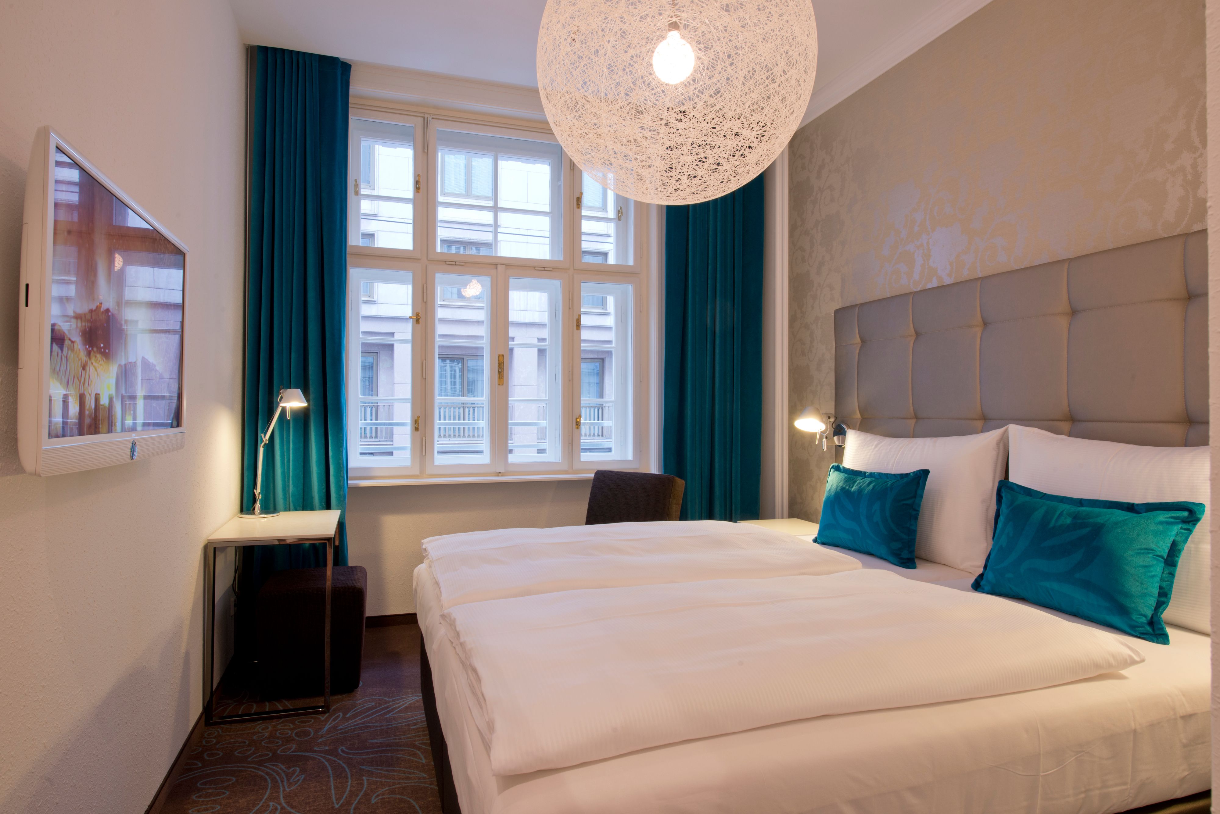 Hotel Wien Staatsoper Motel One Zimmer mit großem Doppelbett und großen Fenstern