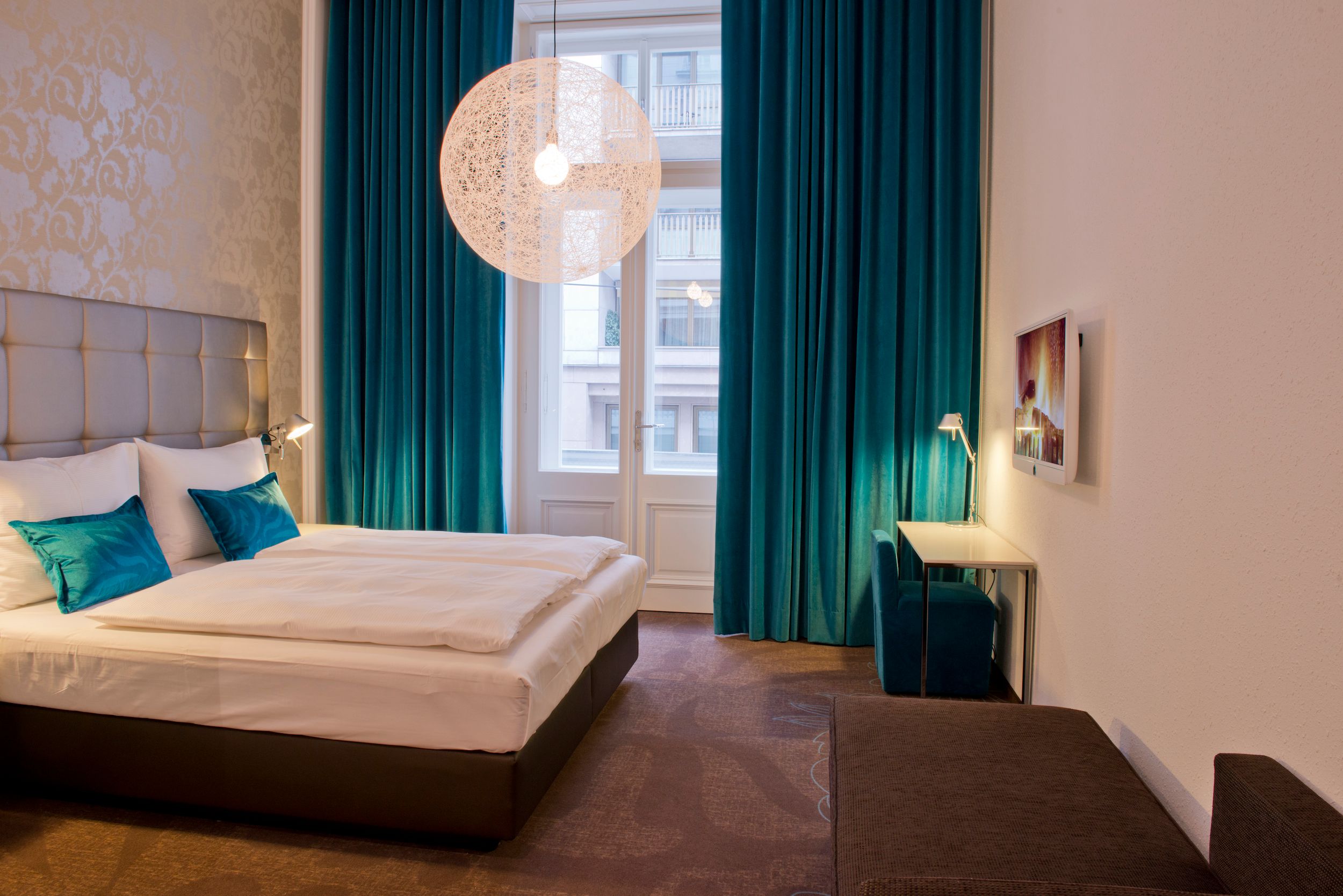 Designhotel Wien Staatsoper Motel One geräumiges Zimmer mit Doppelbett und Fenstern