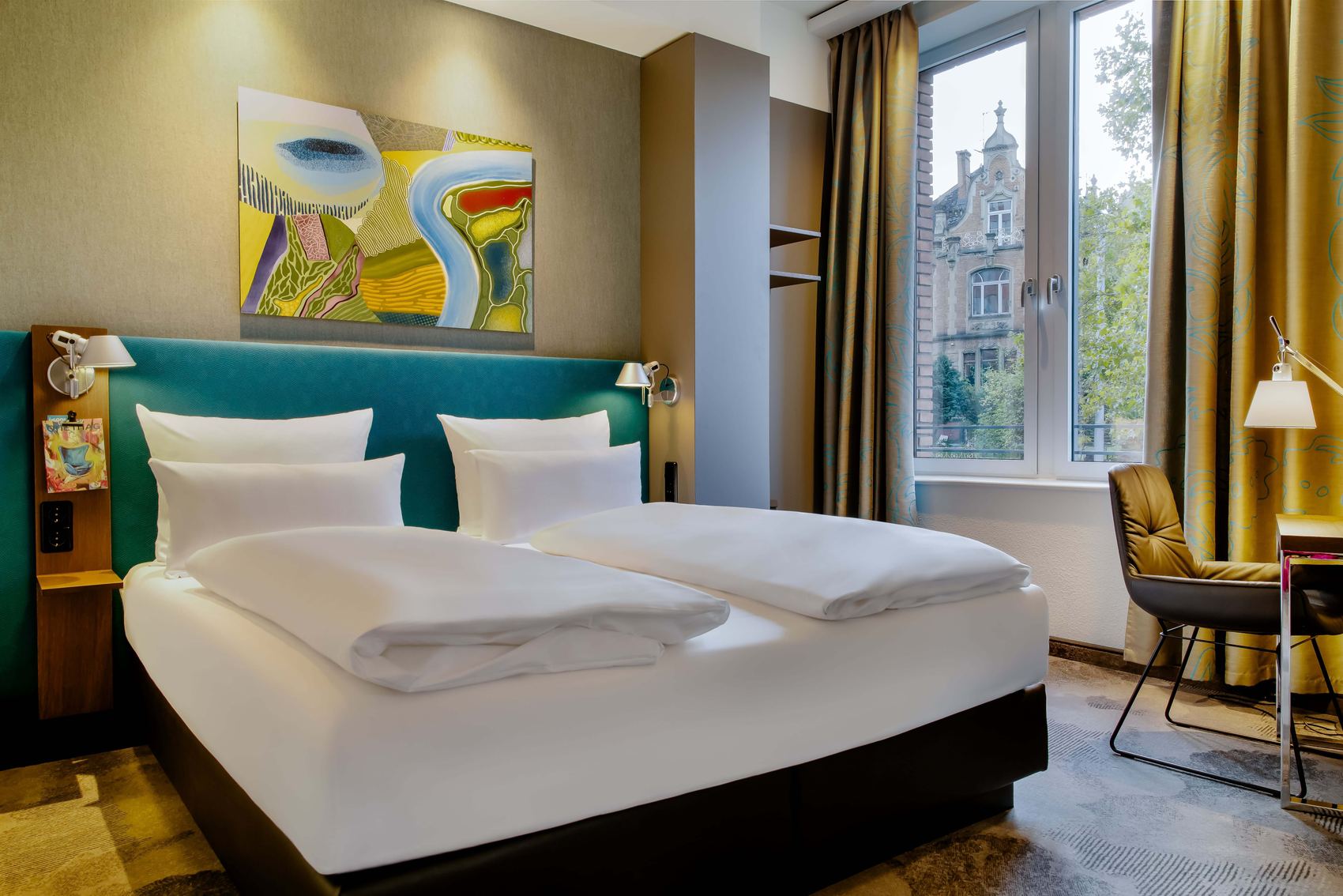 Hotel Wiesbaden Motel One großes Doppelbett mit hellem Fenster und Sessel
