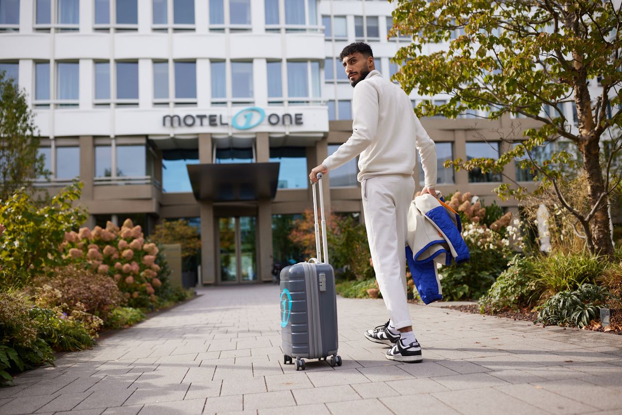 Ahmed with suitcase walking into a Motel One