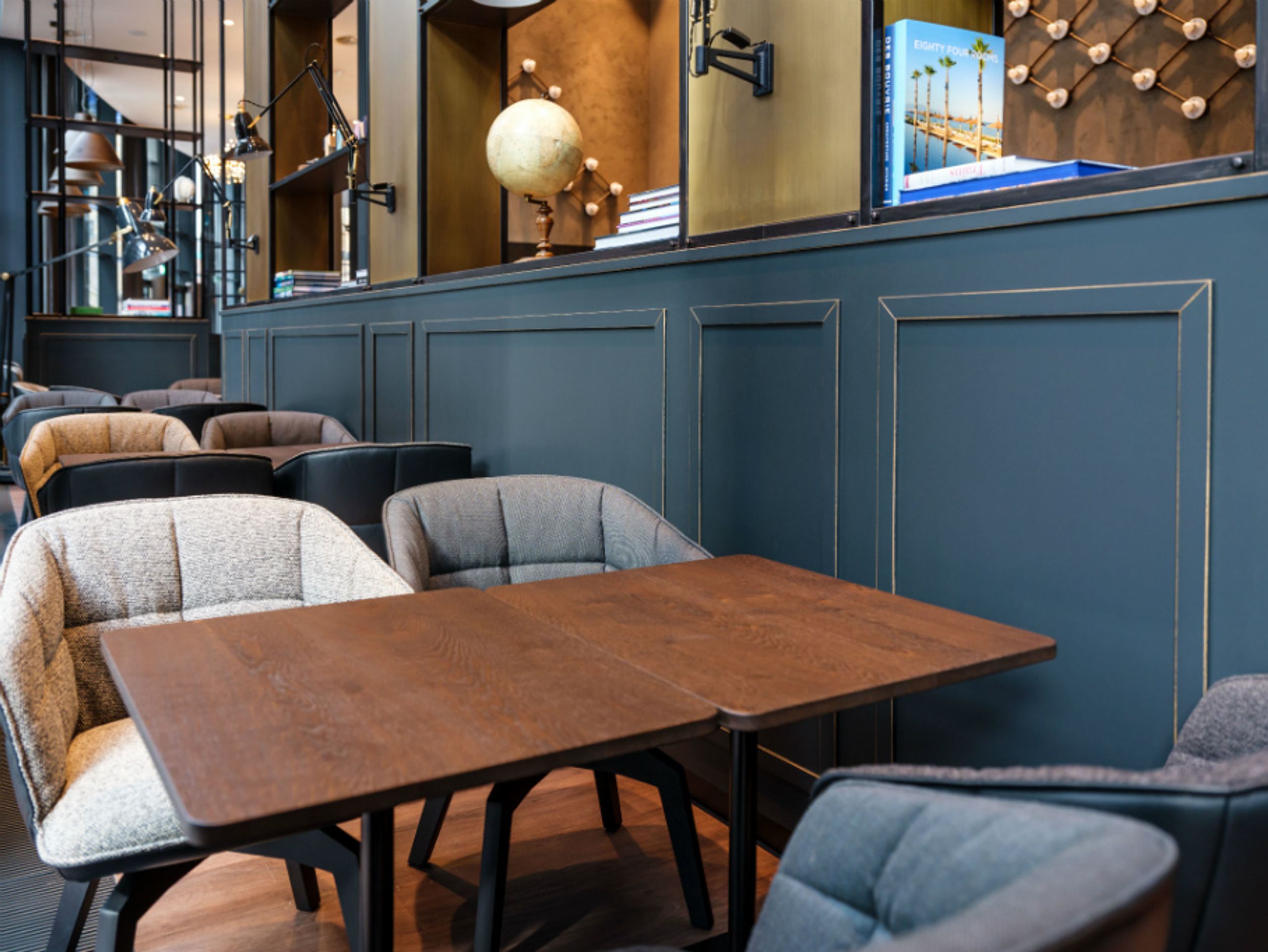 Motel One Sitzbereich mit gepolsterten Sesseln und Holztisch in stilvollem, modern gestaltetem Innenraum.