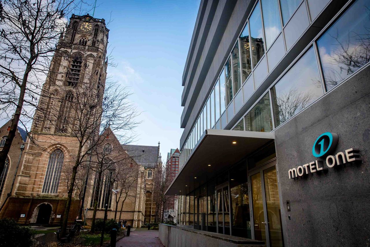 Motel One Hotelgebäude neben einer historischen Kirche, vereint zeitgenössische Architektur mit kulturellem Erbe in zentraler Lage, ideale Unterkunft für Städtereisende.