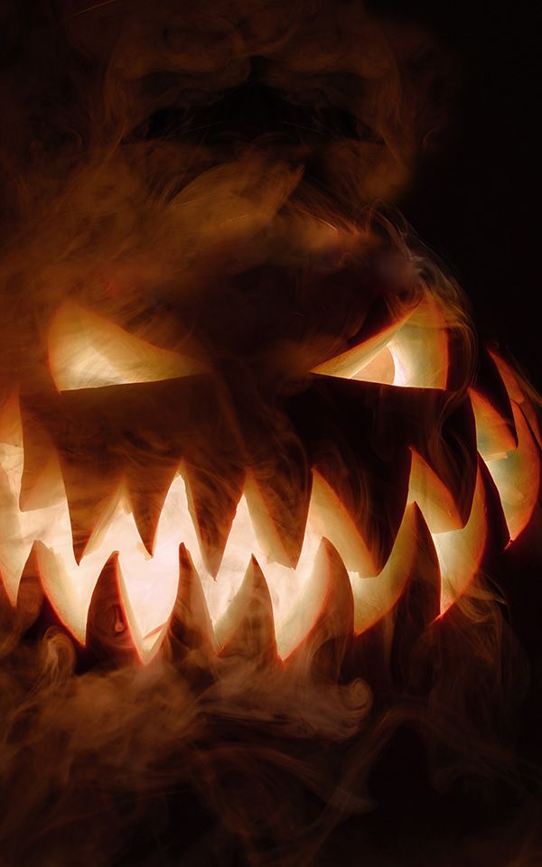 Leuchtender Halloween-Kürbis mit grimmigem Gesichtsausdruck, umgeben von geheimnisvollem Nebel.