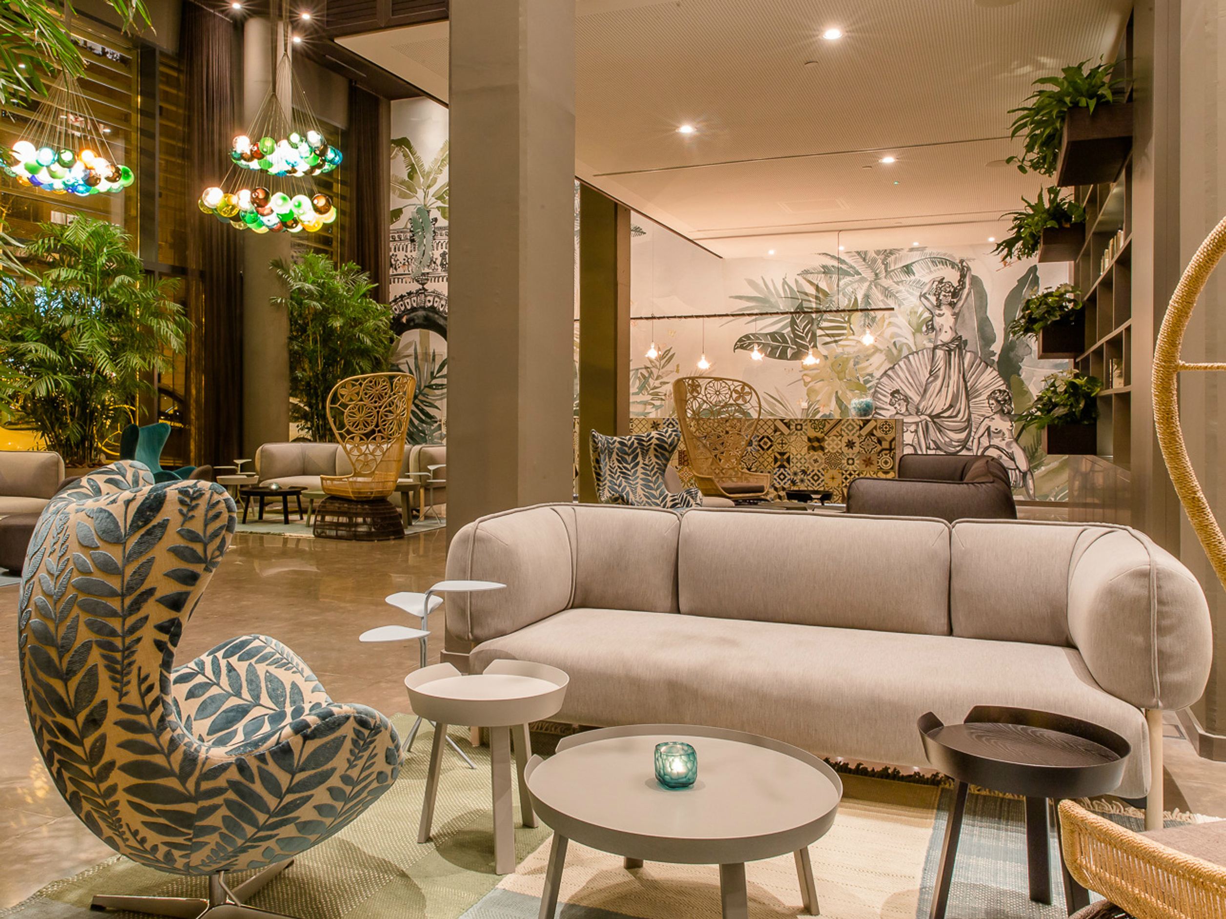 Gemütlicher, stilvoll eingerichteter Hotel-Loungebereich mit modernen Sofas, dekorativen Sesseln und grünen Pflanzen, der eine einladende Atmosphäre zum Entspannen und geselligen Beisammensein bietet.