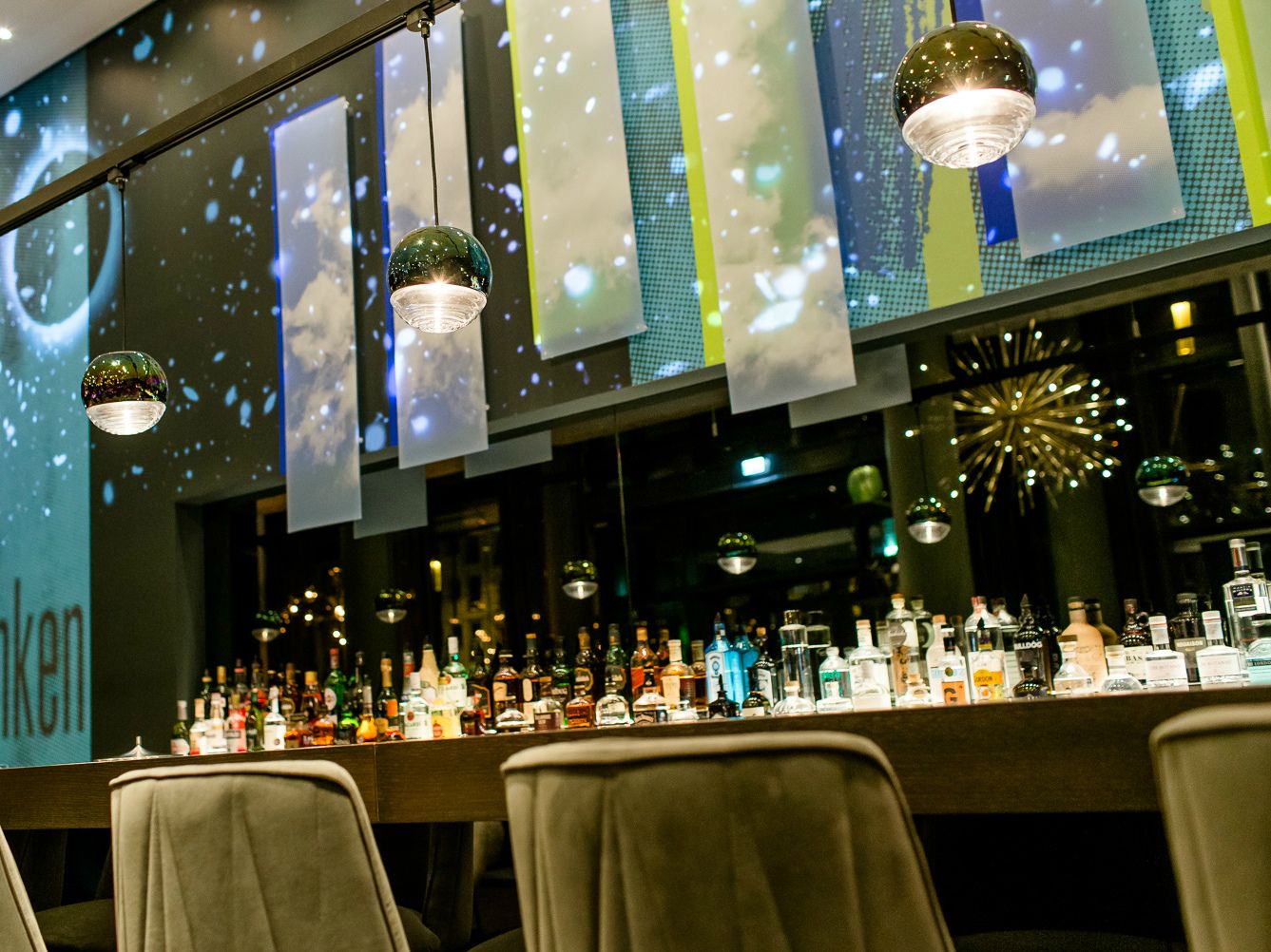 Moderne Hotelbar mit stilvoller Beleuchtung, einer großen Auswahl an Spirituosen und bequemen Sitzmöglichkeiten.