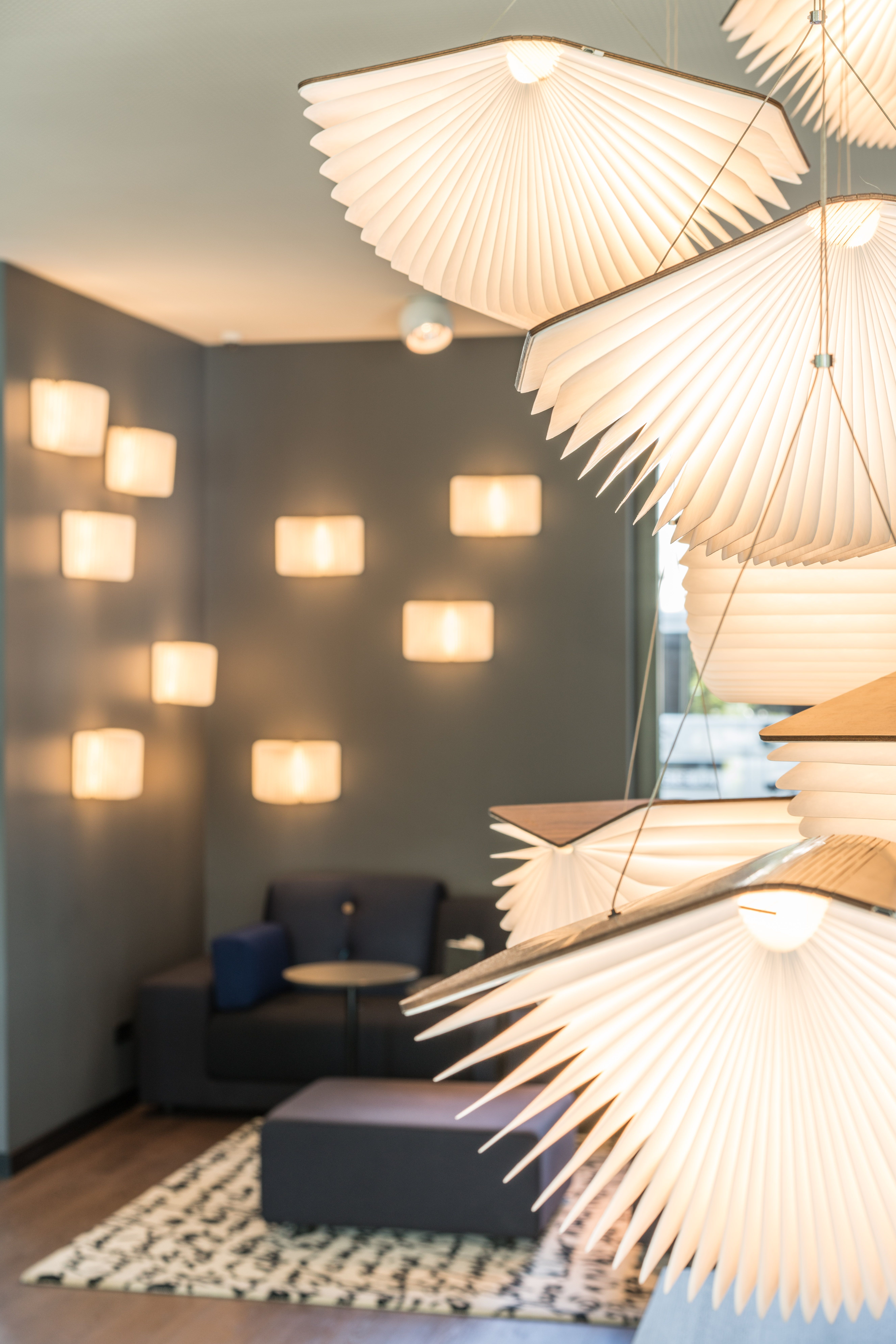 Sanft beleuchteter One Lounge-Bereich mit modernen, dekorativen Lampen, gemütlicher Sitzecke und Teppich