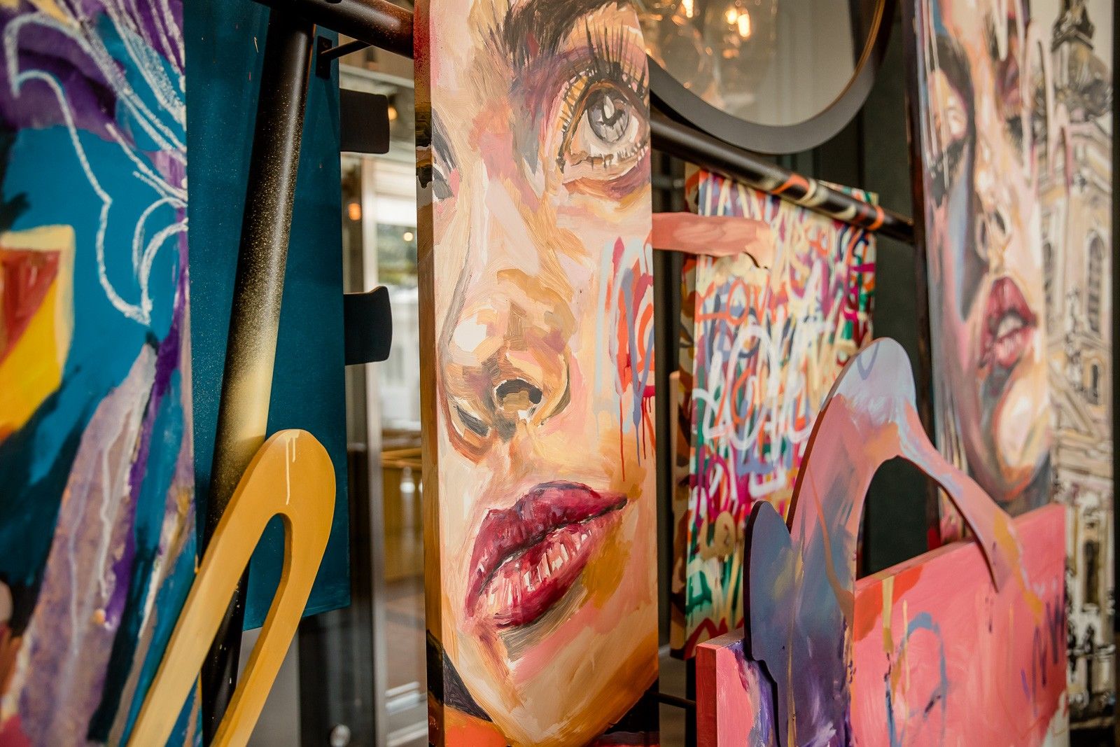 Farbenfrohe, großformatige Gemälde von Gesichtern mit lebendigen, expressiven Pinselstrichen, die Emotionen und Kunst im urbanen Raum vermitteln.