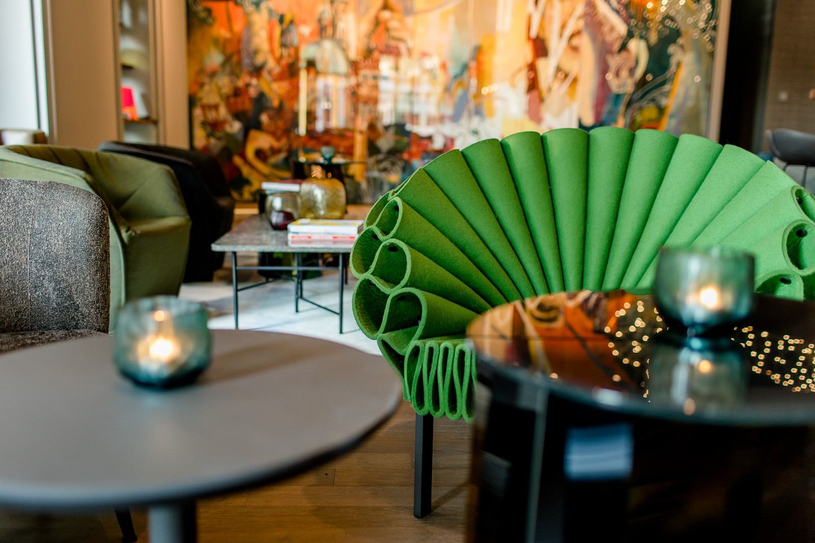 Gemütlicher Lounge-Bereich mit auffälligem, grünem, fächerförmigem Sessel, modernen Tischen und stimmungsvoller Kerzenbeleuchtung für entspannte Momente. Gemütlicher Lounge-Bereich mit auffälligem, grünem, fächerförmigem Sessel, modernen Tischen und stimmungsvoller Kerzenbeleuchtung für entspannte Momente.