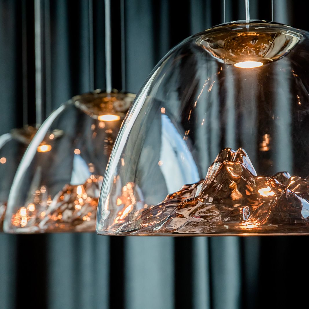 Moderne Design-Hängelampen mit glasklaren Kuppeln, in deren Inneren detailreiche Berglandschaften aus glänzendem Metall geformt sind, strahlen warmes Licht aus