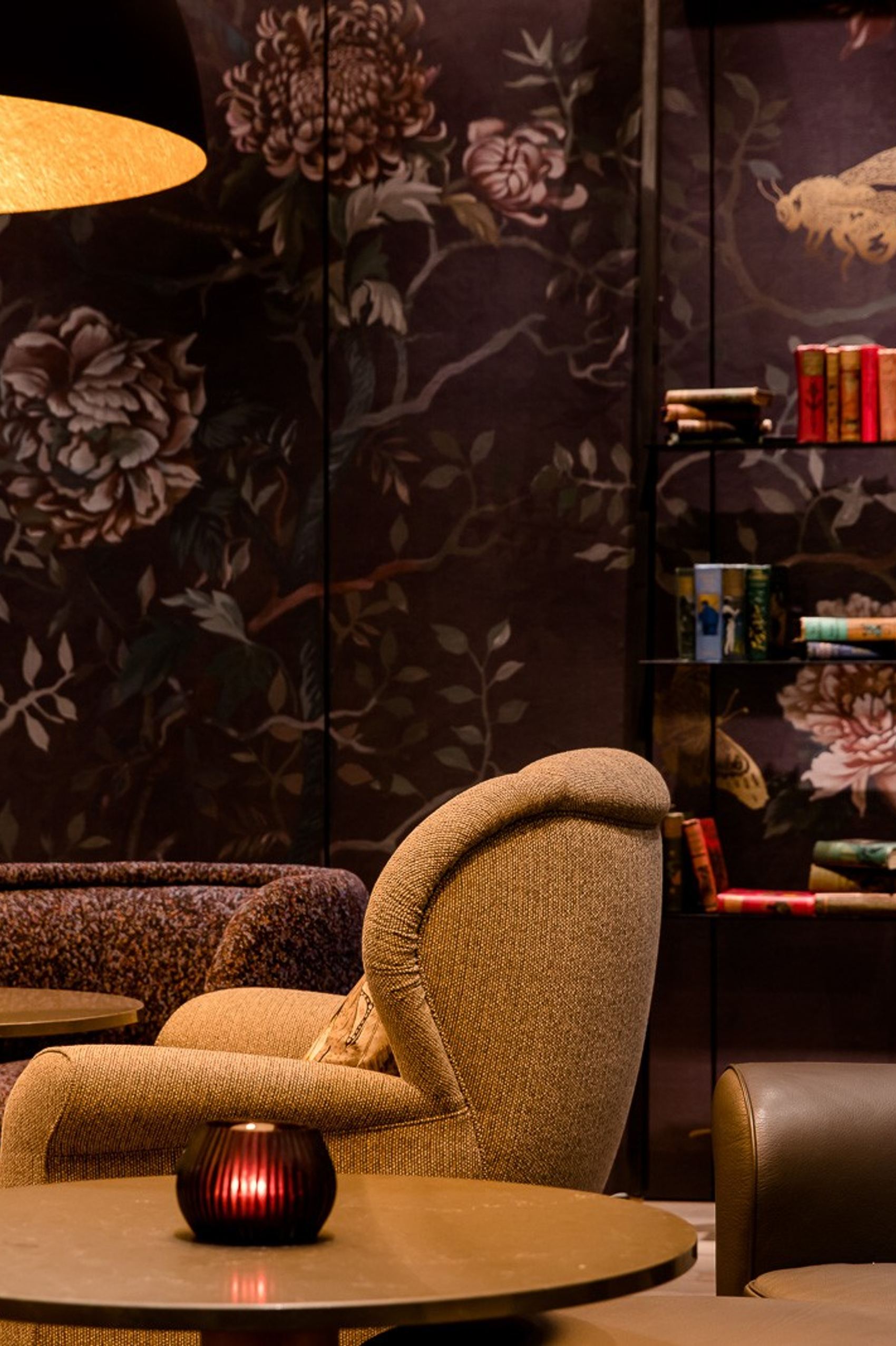 Gemütliche Motel One Lounge mit bequemen Sesseln, dunkler floraler Tapete und warmem Licht