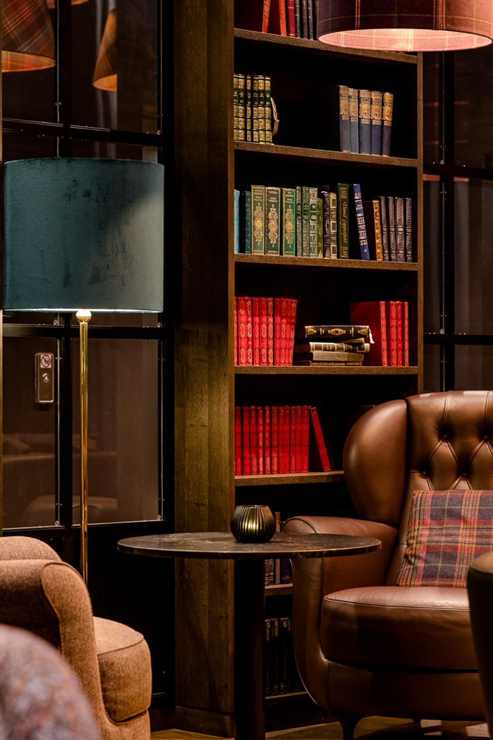 Gemütliche Lounge mit bequemen Sesseln und Teppichen, umgeben von hohen Bücherregalen voller Bücher, schafft eine ruhige Atmosphäre zum Entspannen oder Lesen.