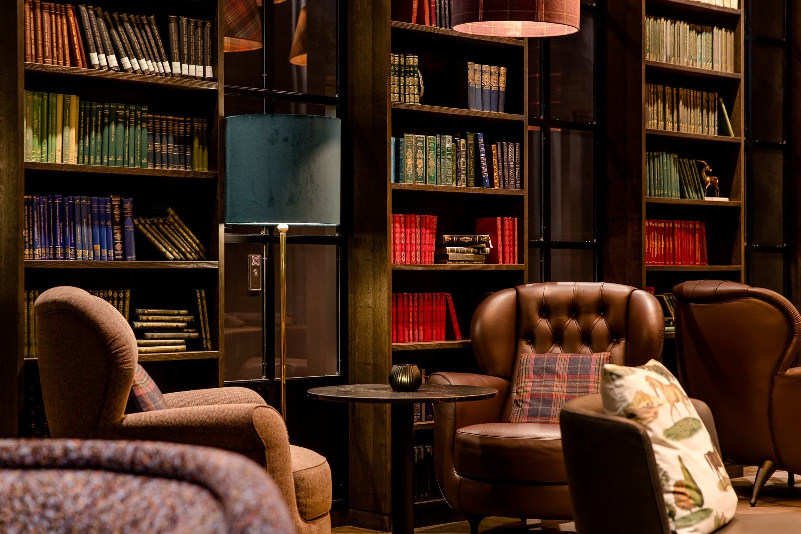 Gemütliche Lounge mit bequemen Sesseln und Teppichen, umgeben von hohen Bücherregalen voller Bücher, schafft eine ruhige Atmosphäre zum Entspannen oder Lesen. Gemütliche Lounge mit bequemen Sesseln und Teppichen, umgeben von hohen Bücherregalen voller Bücher, schafft eine ruhige Atmosphäre zum Entspannen oder Lesen.