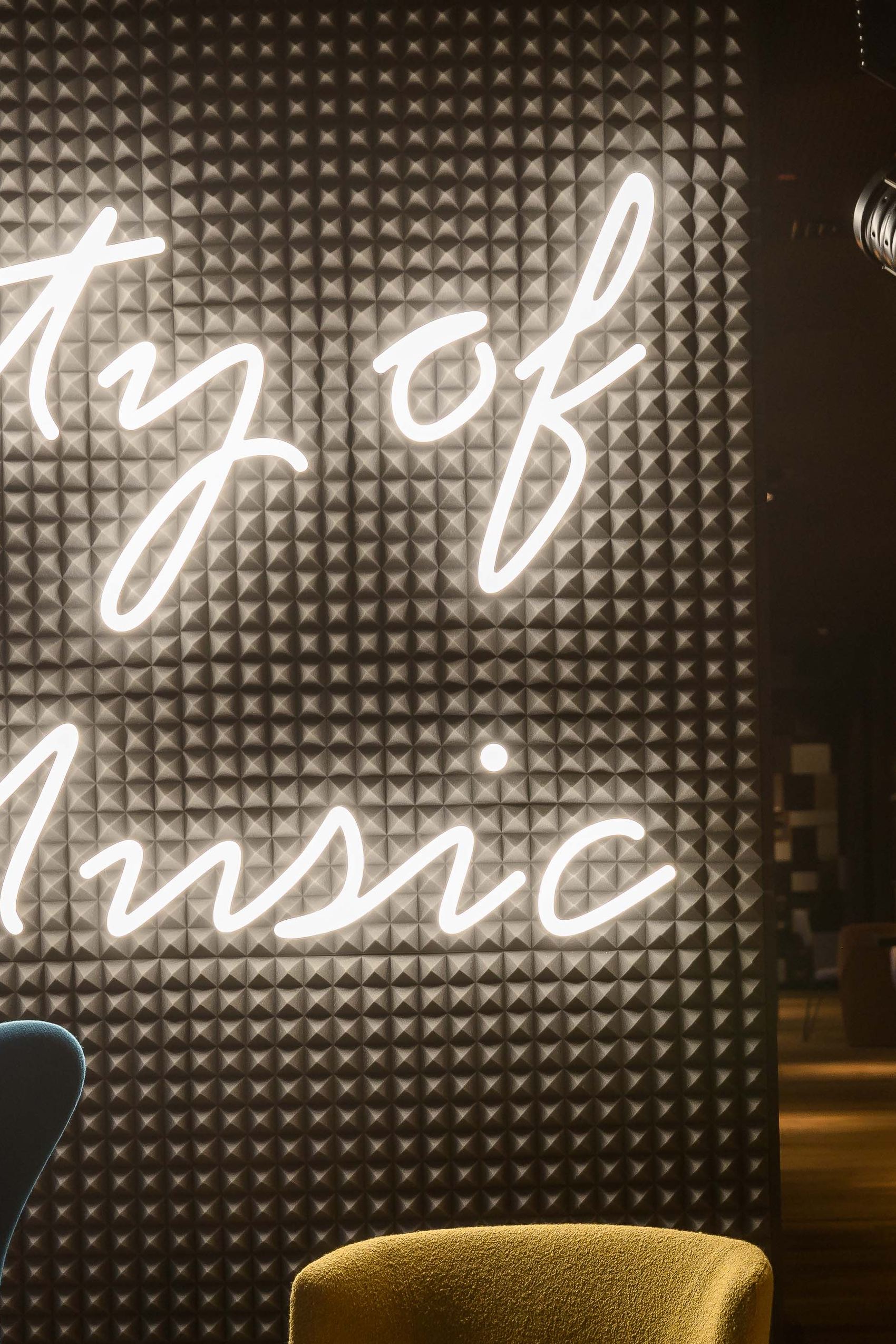 Leuchtendes Wandbild mit der Aufschrift „City of Music“ in stilvoll eingerichteter Lounge mit bequemen Sesseln und gedämpfter Beleuchtung