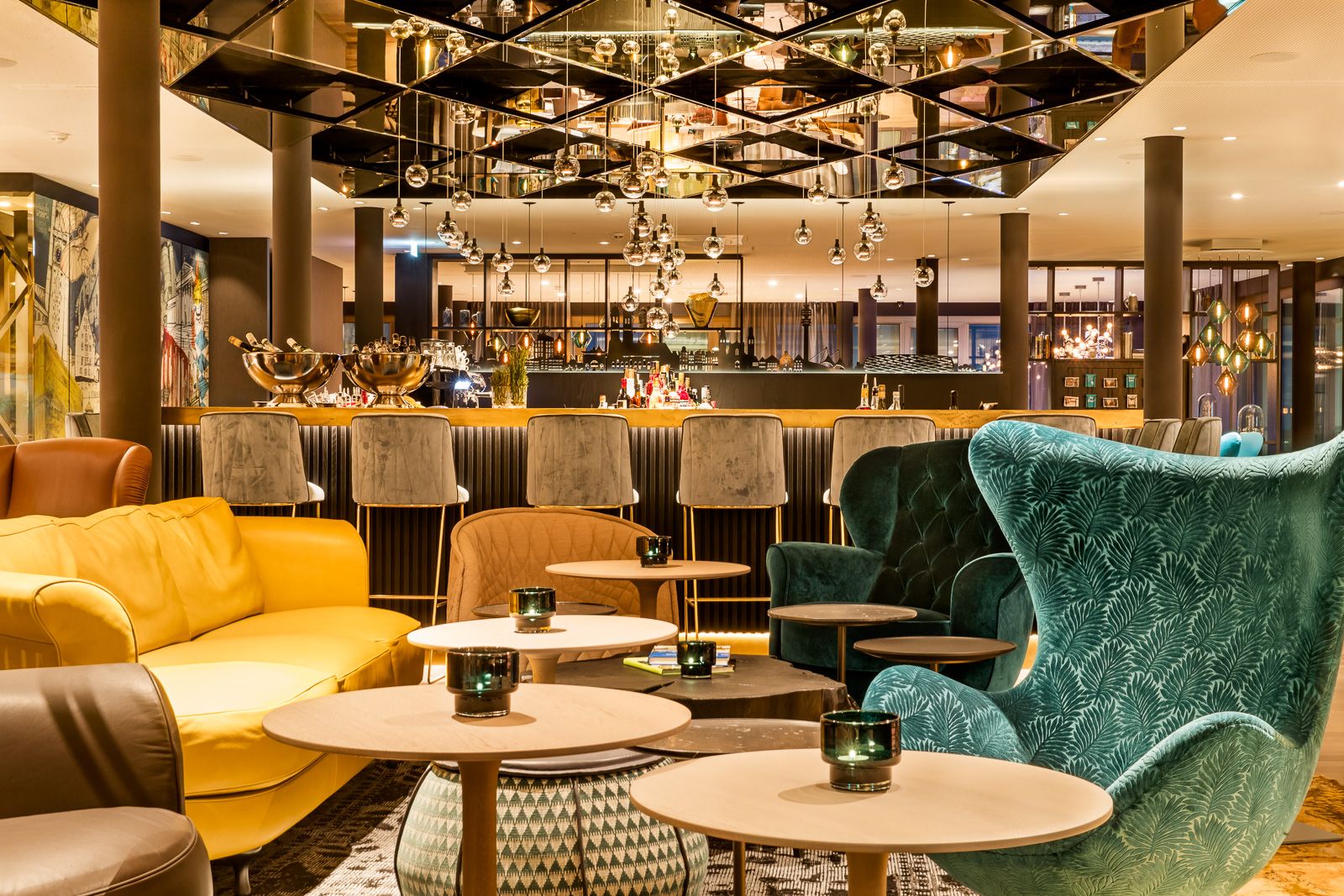 Motel One Hotelbar mit gemütlichen Sesseln und Sofas, runden Tischen, warmem Licht