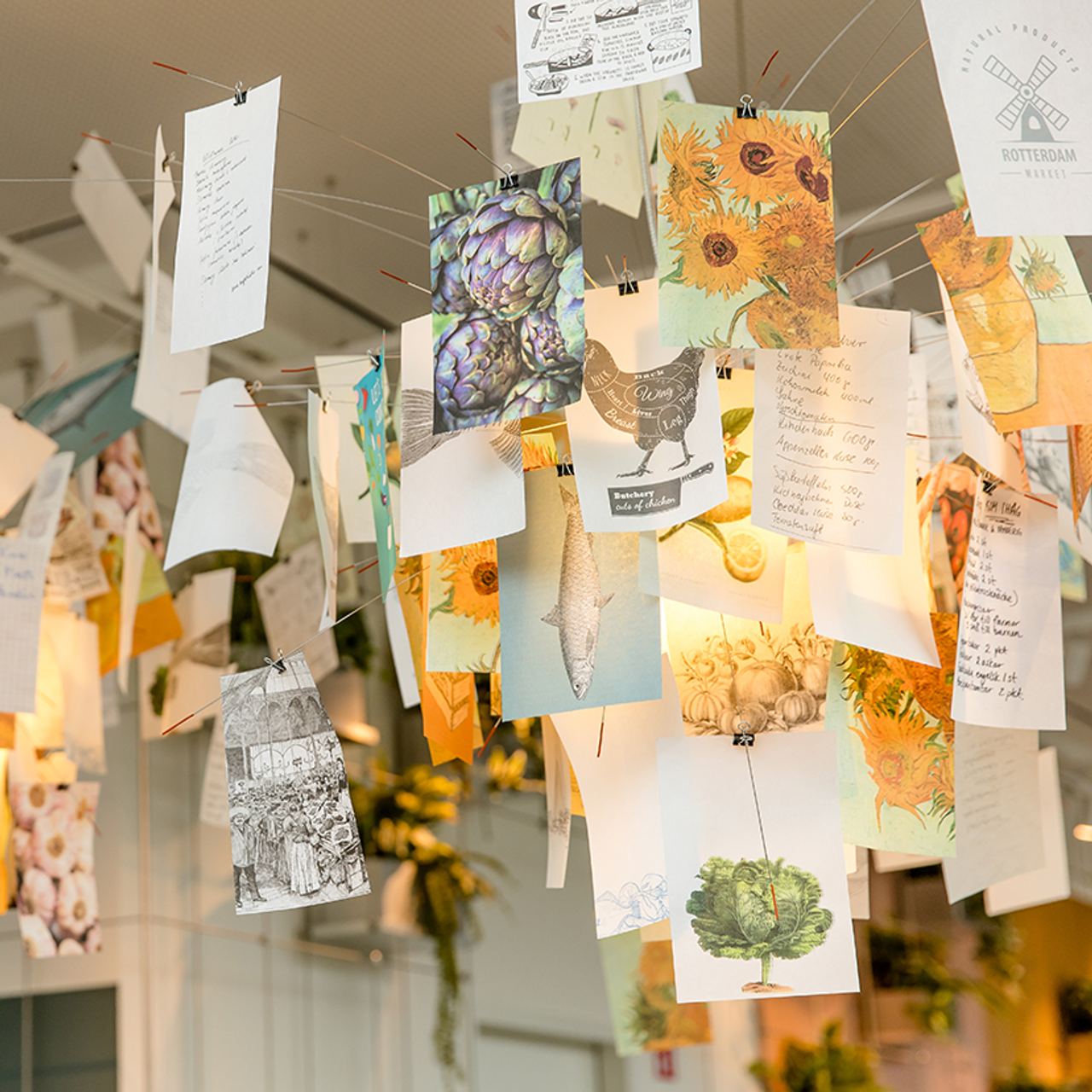 Bunte, künstlerische Postkarten und handgeschriebene Notizen hängen dekorativ von der Decke
