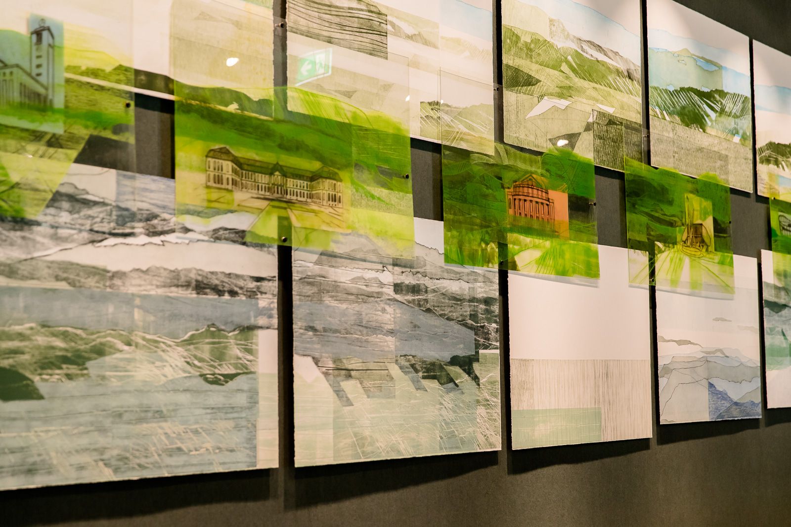 Kunstinstallation mit mehreren übereinander angeordneten Bildern, die Landschaften und Gebäude in grünen und blauen Farbtönen zeigen. 