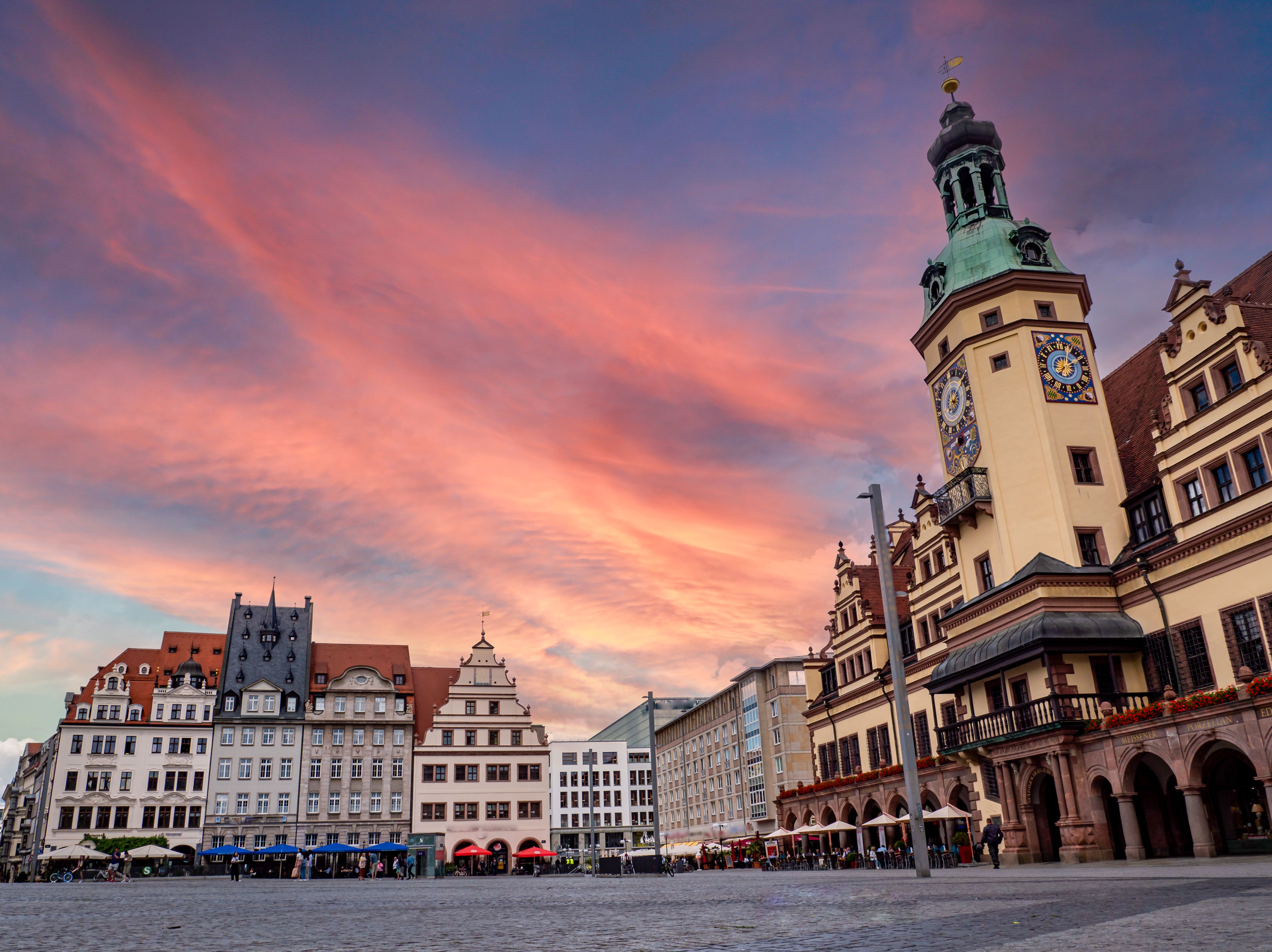 Historischer Marktplatz mit Fachwerkhäusern und dem alten Rathaus bei Sonnenuntergang, der den Himmel in warmen Rosa- und Orangetönen leuchten lässt. Einladende Atmosphäre für Besucher und Reisende, die Kultur und Geschichte der Stadt erleben möchten.