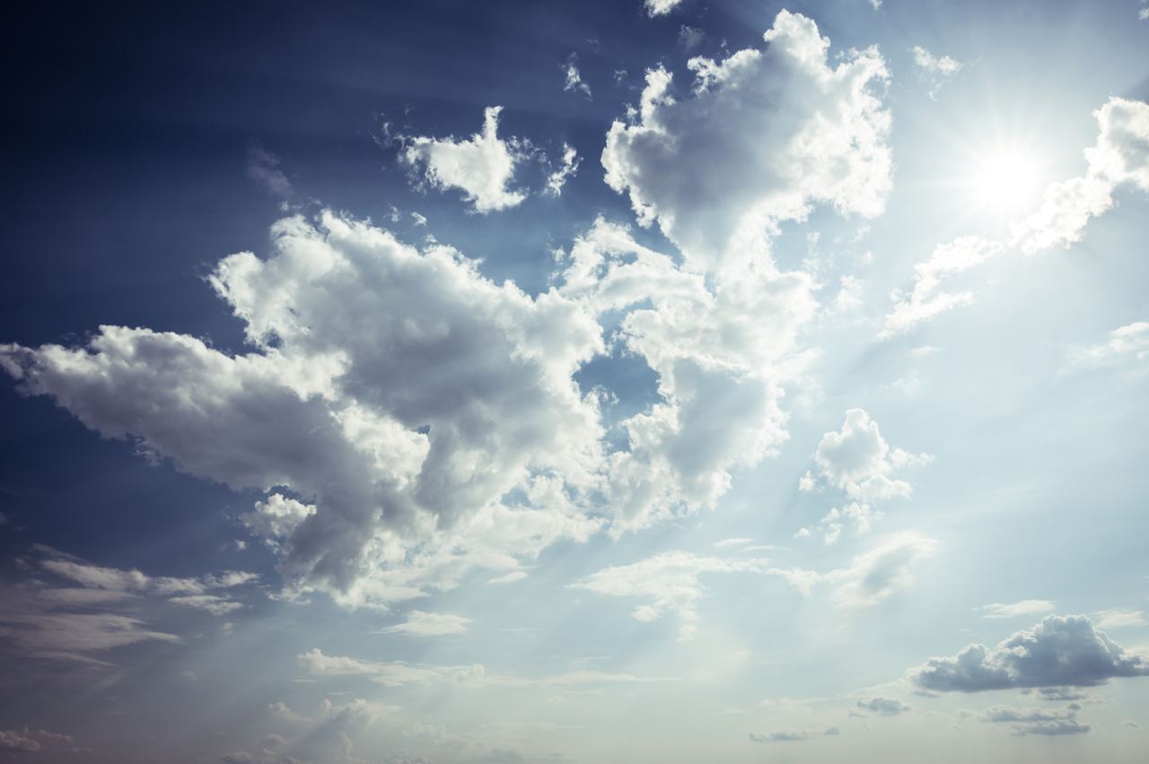 Heller, sonniger Himmel mit vereinzelten, weißen Wolken, der eine friedliche und offene Atmosphäre vermittelt.