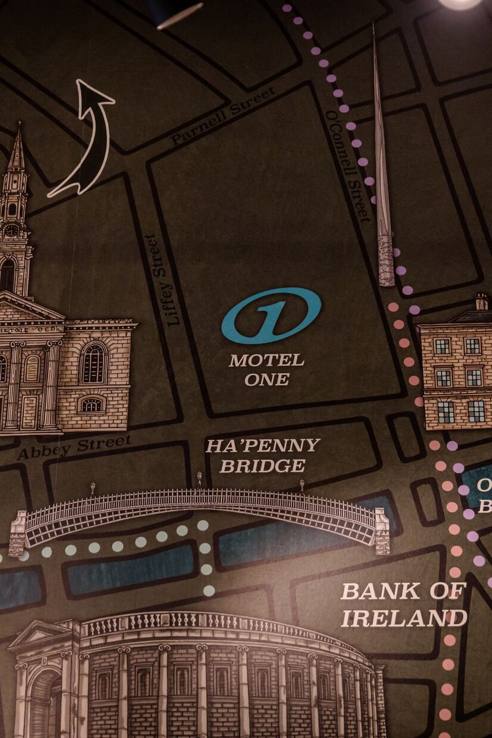 Karte mit Wegbeschreibung zum Motel One, das zwischen Ha’Penny Bridge und O’Connell Bridge an der Abbey Street in Dublin liegt, mit hervorgehobenen Gebäuden und Straßen.