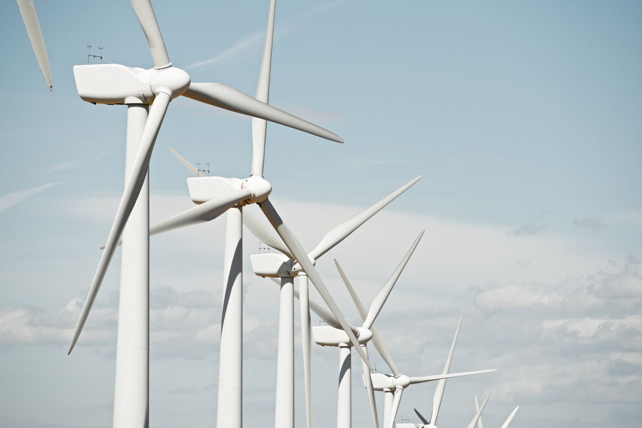 Reihe moderner Windkraftanlagen vor blauem Himmel, symbolisiert nachhaltige Energie und umweltfreundliche Technologie.