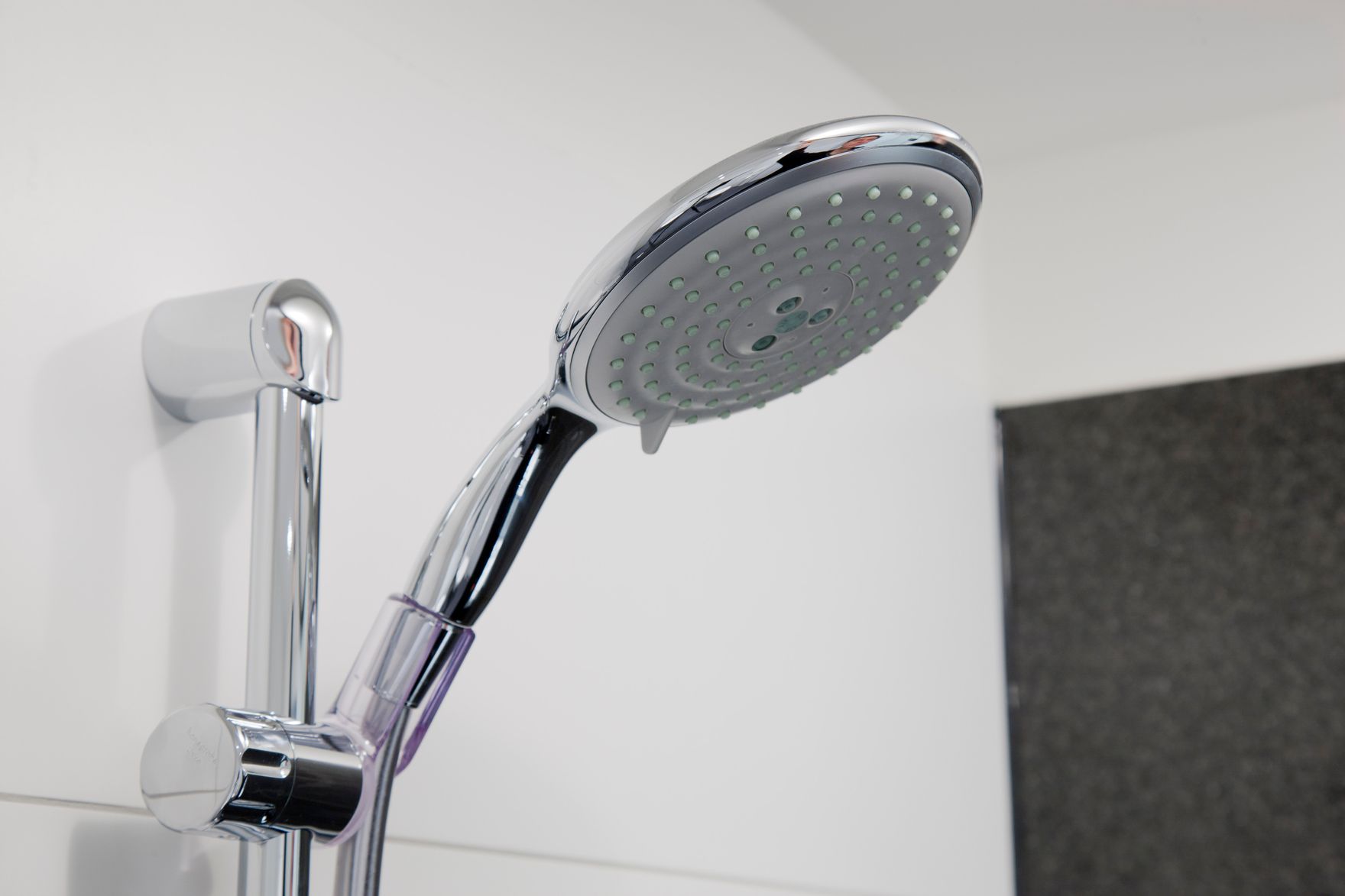Nahaufnahme einer modernen verchromten Handbrause in einer Dusche, die Komfort und zeitgemäßes Design im Badezimmer vermittelt.