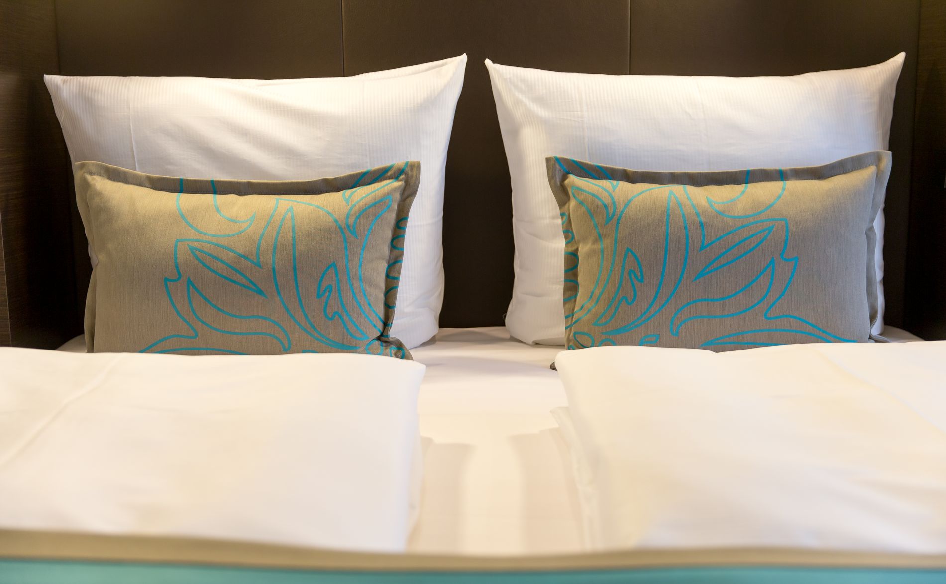 Motel One Zimmer mit zwei frisch bezogenen Kopfkissen mit weißen Bettlaken auf einem Doppelbett, die eine gemütliche und saubere Schlafatmosphäre vermitteln.